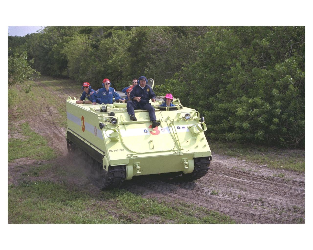 STS-84 crew members ride in and learn how to operate an M-113 armored personnel carrier as part of the Terminal Countdown Demonstration Test (TCDT) activities. In the front seat is Pilot Eileen Marie Collins. George Hoggard, a training officer with KSC Fire Services, sits beside her on top of the personnel carrier. Directly behind Hoggard, from left, are Commander Charles J. Precourt and Mission Specialist Elena V. Kondakova (sitting) of the Russian Space Agency. At the rear, from left, are Mission Specialist C. Michael Foale and Mission Specialist Jean-Francois Clervoy of the European Space Agency. STS-84 aboard the Space Shuttle Atlantis will be the sixth docking of the Space Shuttle with the Russian Space Station Mir. After docking, Foale will transfer to the space station and become a member of the Mir 23 crew, replacing U.S. astronaut Jerry M. Linenger, who will return to Earth aboard Atlantis. Foale will live and work on Mir until mid-September when his replacement is expected to arrive on the STS-86 mission. STS-84 is targeted for a May 15 liftoff