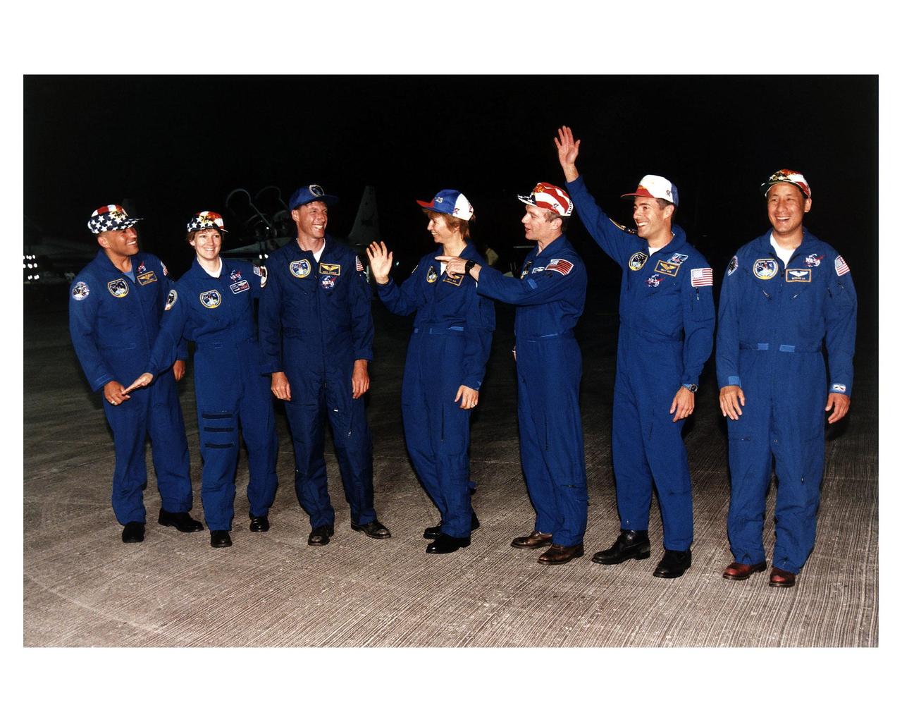 STS-84 crew members greet press representatives and other onlookers after their arrival at KSC’s Shuttle Landing Facility Sunday evening (May 12, 1997), about an hour before the countdown clock will begin ticking toward the scheduled May 15 launch of the Space Shuttle Atlantis on Mission STS-84. From left, are Mission Specialist Carlos I. Noriega, Pilot Eileen Marie Collins, Mission Specialist C. Michael Foale, Mission Specialist Elena V. Kondakova of the Russian Space Agency, Commander Charles J. Precourt, Mission Specialist Jean-Francois Clervoy of the European Space Agency, and Mission Specialist Edward Tsang Lu. STS-84 will be the sixth docking of the Space Shuttle with the Russian Space Station Mir. During the docking, Foale will transfer to the Russian space station to become a member of the Mir 23 crew, replacing U.S. astronaut Jerry M. Linenger, who will return to Earth on Atlantis. Foale is scheduled to remain on Mir about four months until his replacement arrives on STS-86 in September