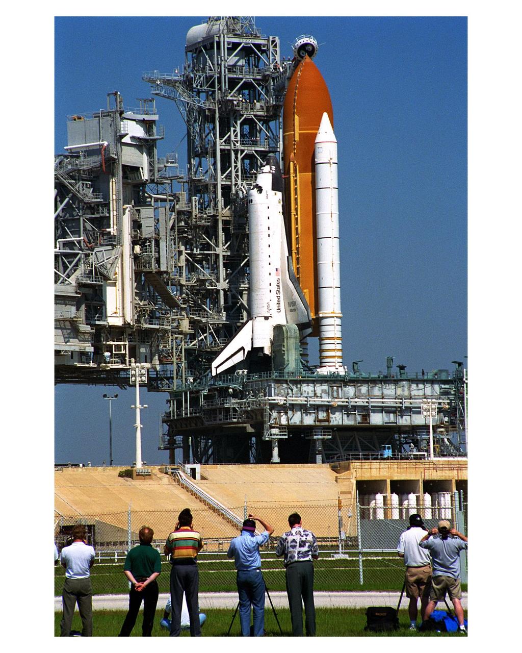 News media representatives watch and record as the Space Shuttle Atlantis in full launch configuration is revealed after the Rotating Service Structure (RSS) is rotated back at Launch Pad 39A. Rollback of the RSS is a major preflight milestone, typically occurring during the T-11-hour hold on L-1 (the day before launch). Atlantis and its crew of seven are in final preparations for liftoff on Mission STS-84, the sixth of nine planned dockings of the Space Shuttle with the Russian Space Station Mir. Launch is scheduled at about 4:08 a.m. during an approximately 7-minute launch window. The exact liftoff time will be determined about 90 minutes prior to launch, based on the most current location of Mir