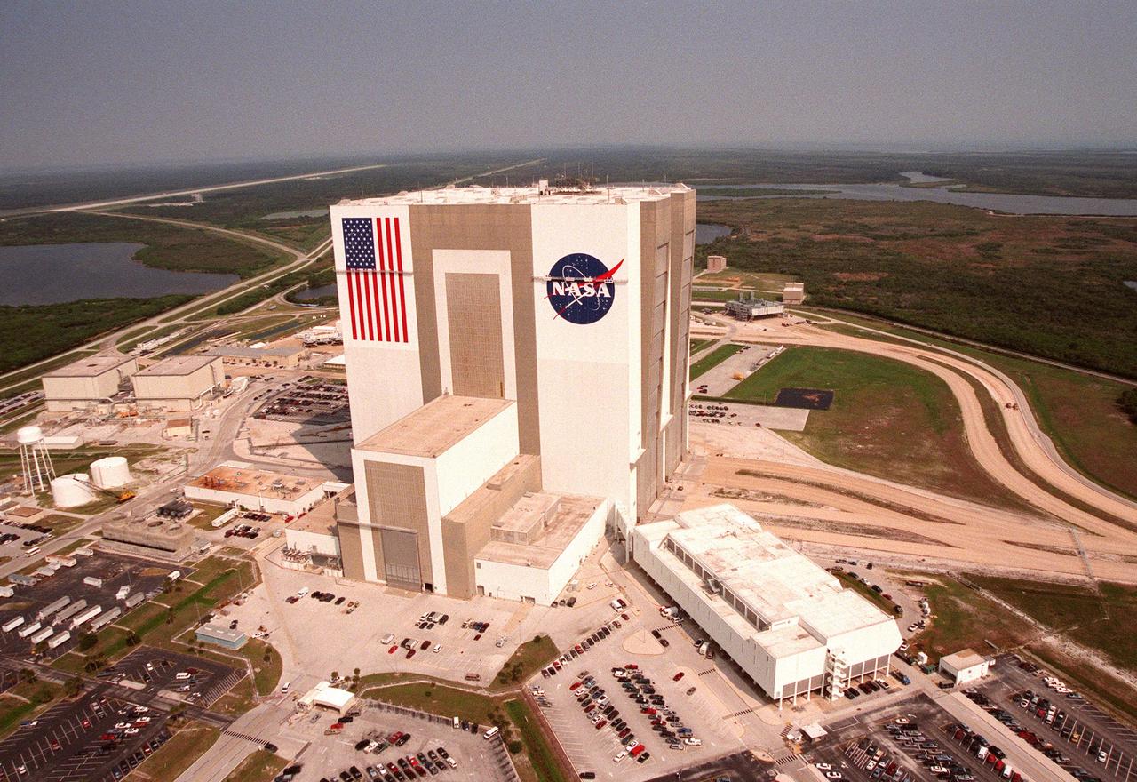 This aerial view shows the Vehicle Assembly Building (VAB) getting a facelift with the repainting of the American flag and replacing of the Bicentennial emblem with the NASA logo. The painting honors NASA's 40th anniversary on Oct. 1 and is expected to be complete in mid-September. The flag spans an area 209 feet by 110 feet, or about 23, 437 square feet. Each stripe is 9 feet wide and each star is 6 feet in diameter. The logo, also known as the 'meatball,' measures 110 feet by 132 feet, or about 12,300 square feet. Workers, suspended on platforms from the top of the 525-foot-high VAB, are using rollers and brushes to do the painting. The entire fleet of orbiters is also receiving the addition of the NASA logo on their wings and sidewalls. 