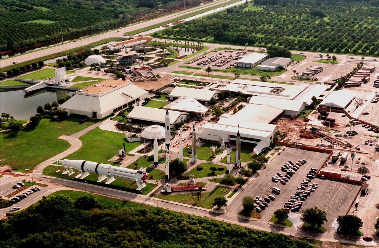 The Kennedy Space Center Visitor Complex, shown in this aerial view looking east, sprawls across 70 acres on Florida's Space Coast. It is located off State Road 405, NASA Parkway, six miles inside the Space Center entrance. SR 405 can be seen at the top left of the photo. In the foreground is the display of rockets that have played a significant role in the growth of the space program. Just above that, left to right, can be seen the Theater Complex, Space Flight Exhibit Building and Spaceport Central. Other buildings clustered at the center are the Cafeteria, Souvenir Sales Building, and Ticket Pavilion. To the left of the Theater Complex are the Astronaut Memorial, the Post Show Dome, and the Shuttle/Gantry mockup. Not seen in the photo is the Center for Space Education. 