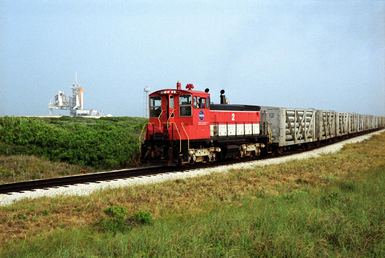 A NASA railroad train moves past Launch Pad 39A at NASA's Kennedy Space Center in Florida. The space agency utilizes railroad operations to not only move equipment at Kennedy, but to transport hardware to and from contractor facilities across the nation. Photo credit: NASA