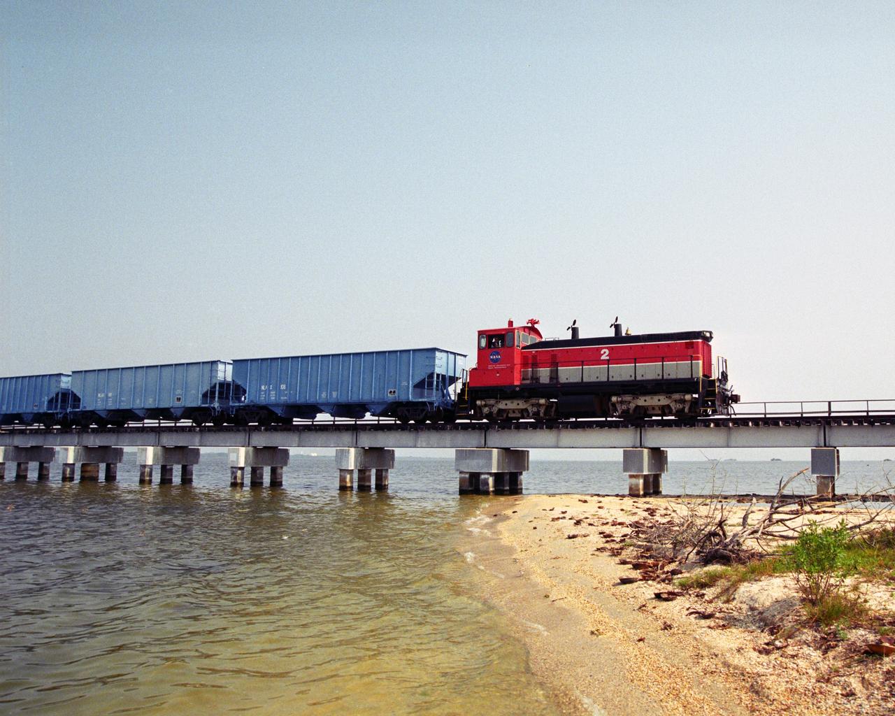 CAPE CANAVERAL, Fla. – A NASA railroad train hauling the solid rocket booster, or SRB, segments moves along the track at NASA's Kennedy Space Center in Florida. The SRB segments are under protective covers. The space agency utilizes railroad operations to not only move equipment at Kennedy, but to transport hardware to and from contractor facilities across the nation. Photo credit: NASA