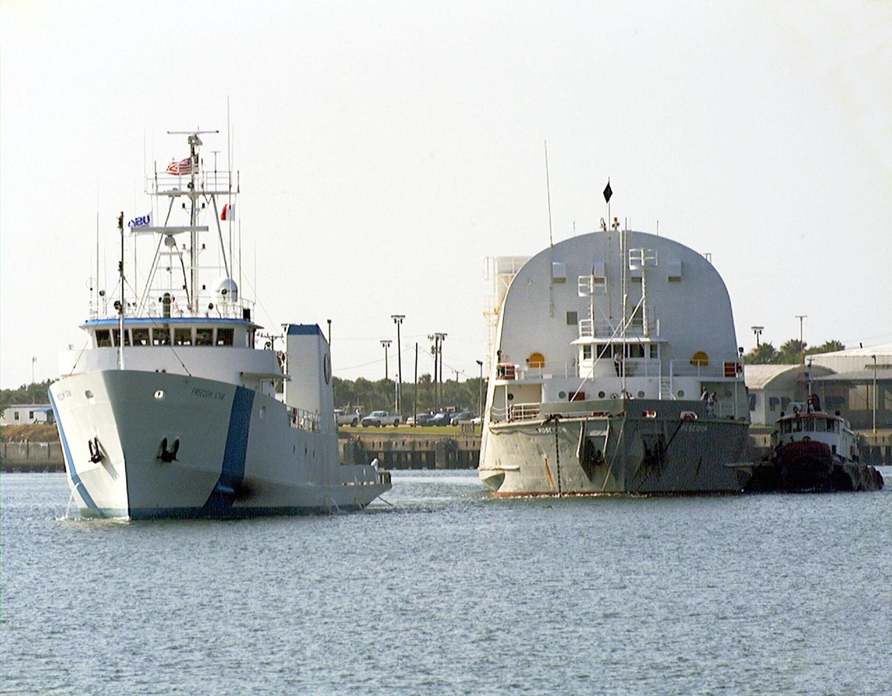 KENNEDY SPACE CENTER, FLA. -- Freedom Star, one of NASA's two solid rocket booster recovery ships, tows a barge containing the third Space Shuttle super lightweight external tank (SLWT) into Port Canaveral. This SLWT will be used to launch the orbiter Discovery on mission STS-95 in October. This first-time towing arrangement, part of a cost savings plan by NASA to prudently manage existing resources, began June 12 from the Michoud Assembly Facility in New Orleans where the Shuttle's external tanks are manufactured. The barge will now be transported up the Banana River to the LC-39 turn basin using a conventional tugboat. Previously, NASA relied on an outside contractor to provide external tank towing services at a cost of about $120,000 per trip. The new plan allows NASA's Space Flight Operations contractor, United Space Alliance (USA), to provide the same service directly to NASA using the recovery ships during their downtime between Shuttle launches. Studies show a potential savings of about $50,000 per trip. The cost of the necessary ship modifications should be paid back by the fourteenth tank delivery. The other recovery ship, Liberty Star, has also undergone deck strengthening enhancements and will soon have the necessary towing winch installed