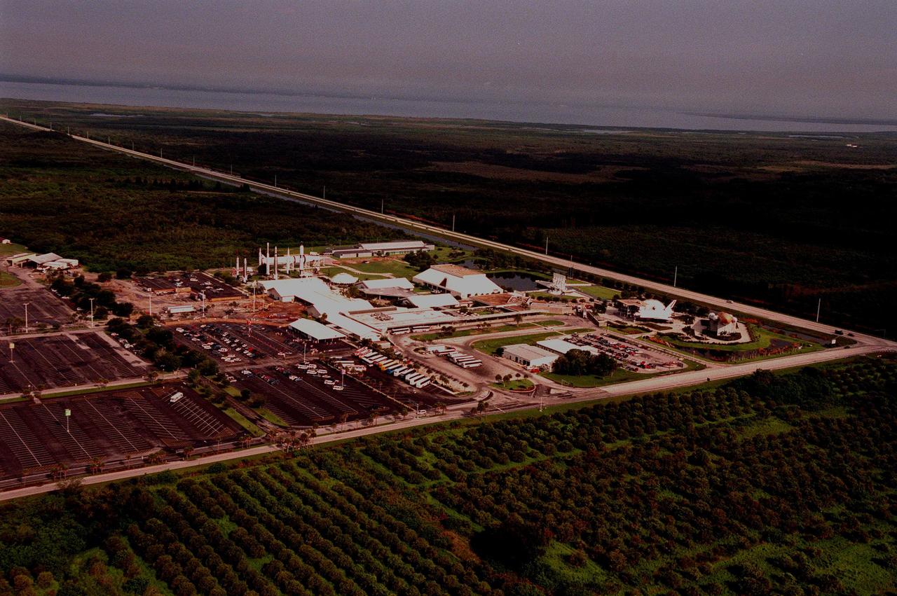 The Kennedy Space Center Visitor Center, shown in this aerial view looking northwest, sprawls across 70 acres on Florida's Space Coast and is located off State Road 405, NASA Parkway, six miles inside the Space Center entrance. SR 405 can be seen at the top of the photo (left to right). Just below the roadway, from left, can be seen the Center for Space Education, the Theater Complex, Astronaut Memorial, the Post Show Dome, and Shuttle/Gantry mockup. In front of the theater complex are a cluster of buildings that include the Cafeteria, Space Flight Exhibit Building, Souvenir Sales Building, Spaceport Central, and Ticket Pavilion. At the left of the complex are various rockets that have played a significant role in the growth of the space program. Beyond the roadway can be seen the Banana River. 