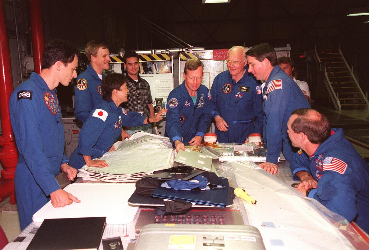 Around a table in Orbiter Processing Facility Bay 2 , STS-95 crew members look over equipment during the Crew Equipment Interface Test (CEIT) for their mission. From left, they are Mission Specialist Pedro Duque, of the European Space Agency; Payload Specialist Chiaki Mukai, of the National Space Development Agency of Japan (NASDA); Mission Specialist Scott E. Parazynski, M.D.; Pilot Steven W. Lindsey; Payload Specialist John H. Glenn Jr., senator from Ohio; Mission Specialist Stephen K. Robinson; and Mission Commander Curtis L. Brown Jr. Behind them is Adam Flagan, United Space Alliance-Houston. The CEIT gives astronauts an opportunity for a hands-on look at the payloads and equipment with which they will be working on orbit. The launch of the STS-95 mission, aboard Space Shuttle Discovery, is scheduled for Oct. 29, 1998. The mission includes research payloads such as the Spartan solar-observing deployable spacecraft, the Hubble Space Telescope Orbital Systems Test Platform, the International Extreme Ultraviolet Hitchhiker, as well as the SPACEHAB single module with experiments on space flight and the aging process
