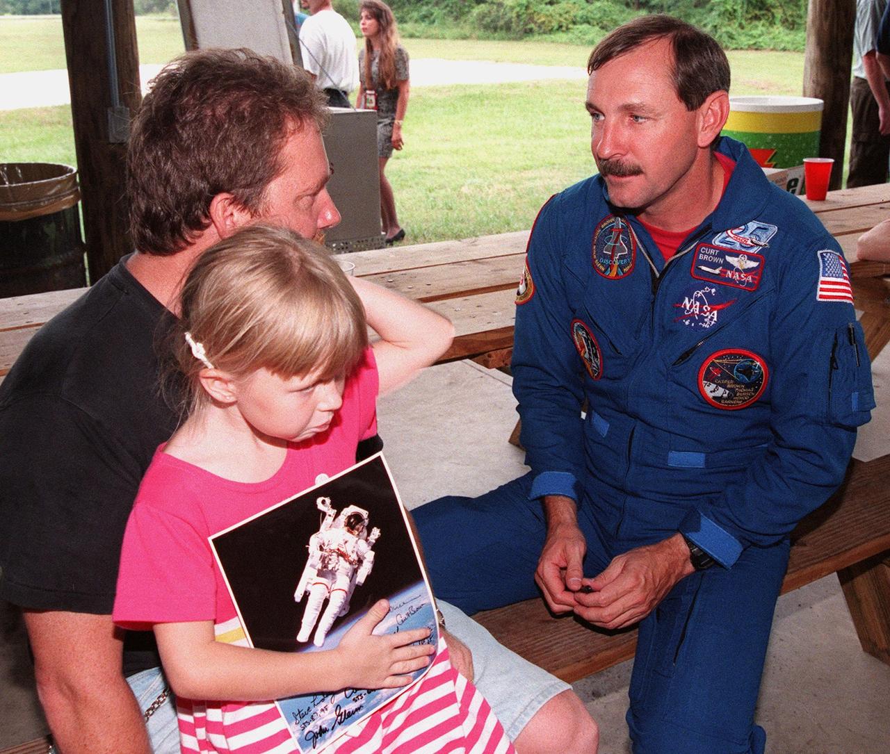During a break in the Crew Equipment Interface Test (CEIT) at KSC, STS-95 Mission Commander Curtis L. Brown Jr. talks to Mark King, a Space Shuttle midbody mechanical technician with United Space Alliance, and his daughter Jilianne. King is working in the Orbiter Processing Facility Bay 2 on STS-95 payloads. The CEIT gives astronauts an opportunity for a hands-on look at the payloads and equipment which they will be working with on orbit. The launch of the STS-95 mission is scheduled for Oct. 29, 1998, on the Space Shuttle Discovery. The mission includes research payloads such as the Spartan solar-observing deployable spacecraft, the Hubble Space Telescope Orbital Systems Test Platform, the International Extreme Ultraviolet Hitchhiker, as well as the SPACEHAB single module with experiments on space flight and the aging process