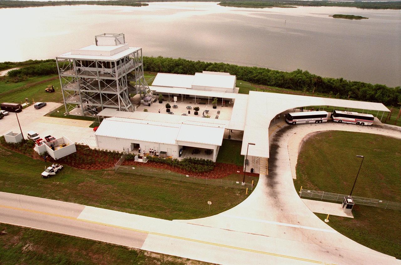 Tour buses unload passengers at a new stop on the KSC tour that allows visitors to view Pad LC-39B. The tour road runs parallel to the crawlerway (just out of sight) that is used to transport the Space Shuttle vehicles to the pad. The length of the crawlerway from the Vehicle Assembly Building to Pad B is 6,828 meters (22,440 ft); its width overall is 40 meters (130 ft); each lane is 12 meters (40ft) with a 15-meter (50ft) median. This view looks south