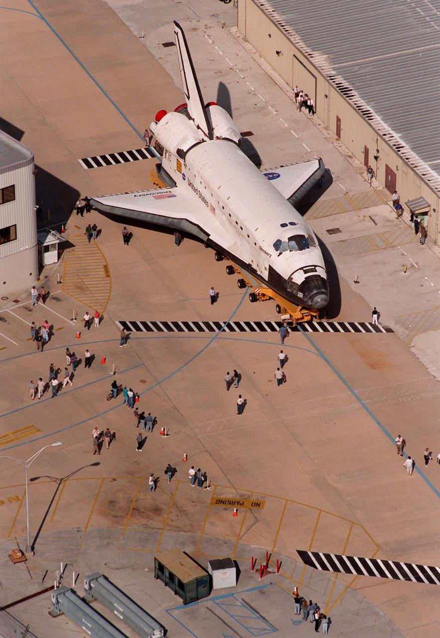 The orbiter Discovery is moved from the Orbiter Processing Facility Bay 2 to the Vehicle Assembly Building, drawing the attention of KSC employees. The orbiter displays the recently painted NASA logo, termed the "meatball," on its left wing and both sides of the fuselage. Discovery (OV-103) is scheduled for its 25th flight, from Launch Pad 39B, on Oct. 29, 1998, for the STS-95 mission