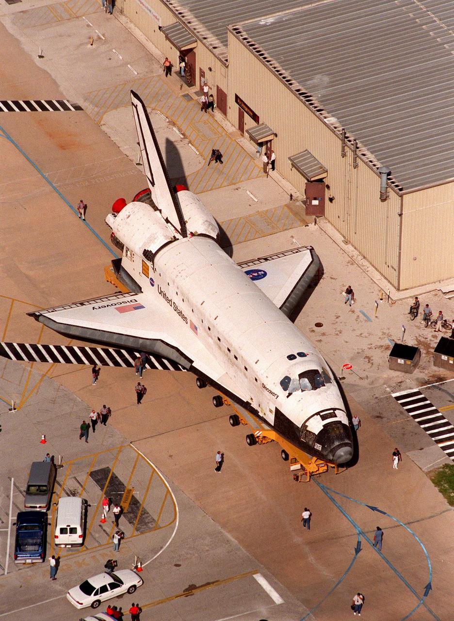 Rollover of the orbiter Discovery from the Orbiter Processing Facility Bay 2 to the Vehicle Assembly Building draws the attention of KSC employees. The orbiter displays the recently painted NASA logo, termed the "meatball," on its left wing and both sides of the fuselage. Discovery (OV-103) is scheduled for its 25th flight, from Launch Pad 39B, on Oct. 29, 1998, for the STS-95 mission