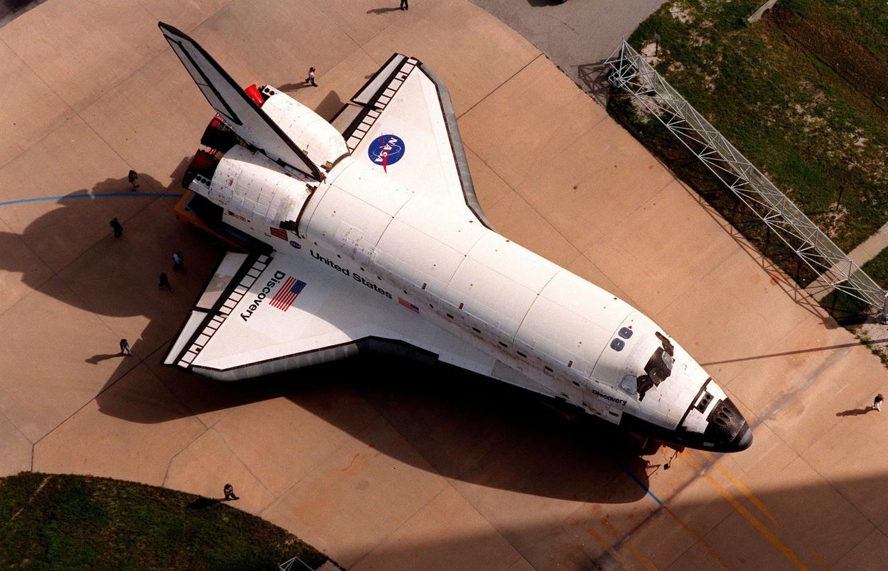 Morning shadows frame the orbiter Discovery on its rollover from the Orbiter Processing Facility Bay 2 to the Vehicle Assembly Building. The orbiter displays the recently painted NASA logo, termed the "meatball," on its left wing and both sides of the fuselage. Discovery (OV-103) is scheduled for its 25th flight, from Launch Pad 39B, on Oct. 29, 1998, for the STS-95 mission