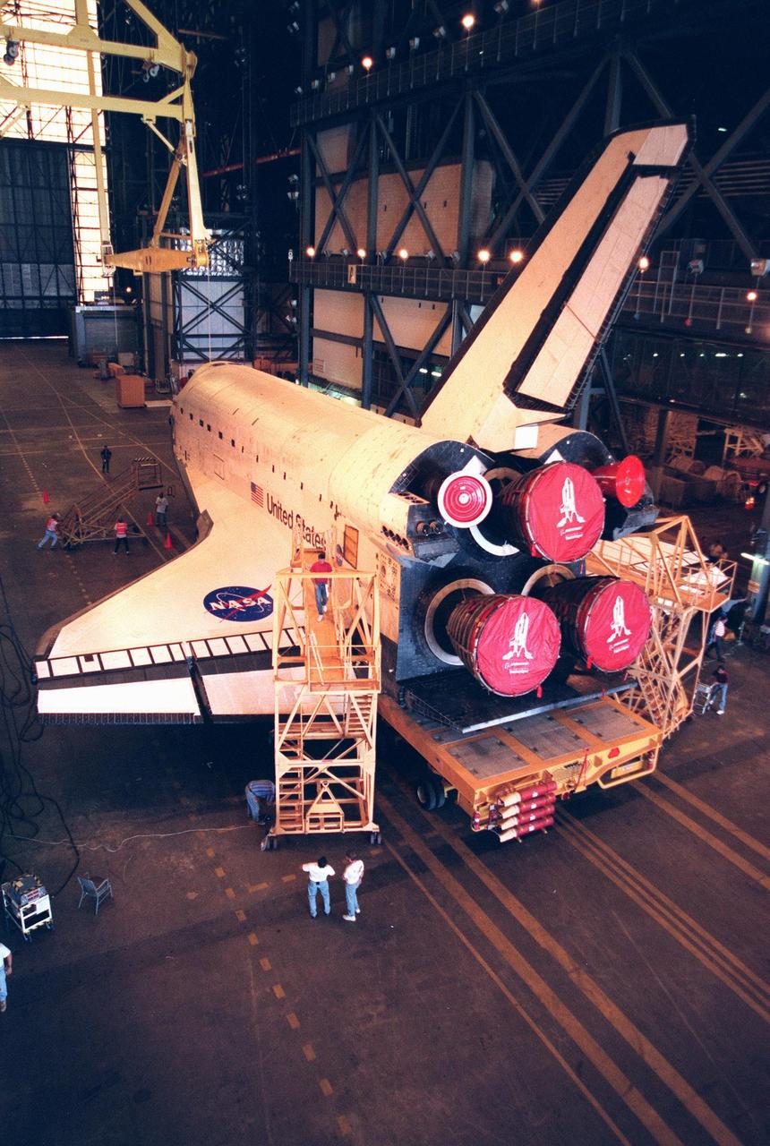 In the Vehicle Assembly Building, workers prepare the orbiter Discovery for vertical lift before mating it with the external tank. The orbiter displays the recently painted NASA logo, termed the "meatball," on its left wing and both sides of the fuselage. Discovery (OV-103) is scheduled for its 25th flight, from Launch Pad 39B, on Oct. 29, 1998, for the STS-95 mission