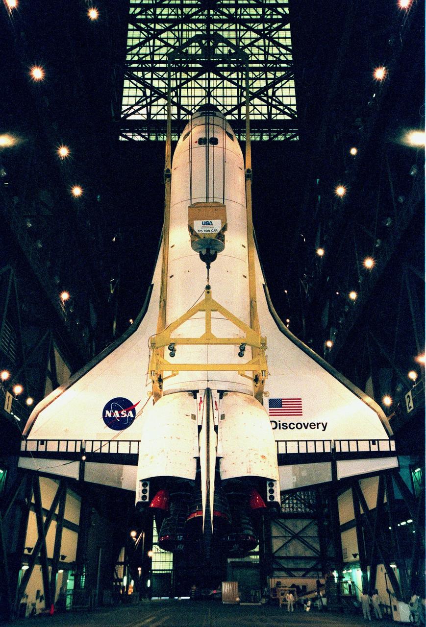 In the Vehicle Assembly Building, the orbiter Discovery is fully vertical, after being lifted into position for mating with the external tank. The orbiter displays the recently painted NASA logo, termed the "meatball," on its left, or port, wing. The logo also has been painted on both sides of the aft fuselage. Discovery (OV-103), the first of the orbiters to be launched with the new art work, is scheduled for its 25th flight, from Launch Pad 39B, on Oct. 29, 1998, for the STS-95 mission