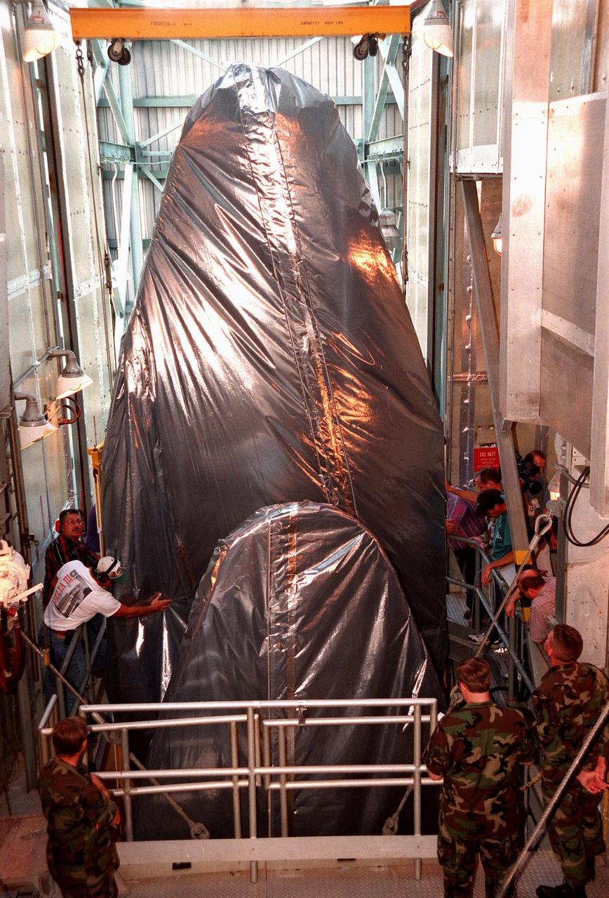 KENNEDY SPACE CENTER, FLA. -- Workers check the position of the fairing for Deep Space 1 as it reaches the top of the Mobile Service Tower where it will be attached to the Boeing Delta 7326 rocket that will launch on Oct. 15, 1998. The first flight in NASA's New Millennium Program, Deep Space 1 is designed to validate 12 new technologies for scientific space missions of the next century. Onboard experiments include an ion propulsion engine and software that tracks celestial bodies so the spacecraft can make its own navigation decisions without the intervention of ground controllers. Deep Space 1 will complete most of its mission objectives within the first two months, but will also do a flyby of a near-Earth asteroid, 1992 KD, in July 1999
