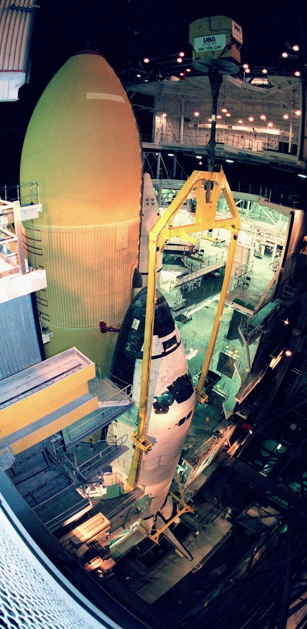 In the Vehicle Assembly Building, the orbiter Discovery is mated with the external tank and solid rocket booster stack (seen behind the orbiter, to the left). The orbiter was recently painted with the NASA logo, termed the "meatball," on the left, or port, wing and both sides of the aft fuselage. Discovery (OV-103) is the first of the orbiters to be launched with the new artwork. It is scheduled for its 25th flight, from Launch Pad 39B, on Oct. 29, 1998, for the STS-95 mission