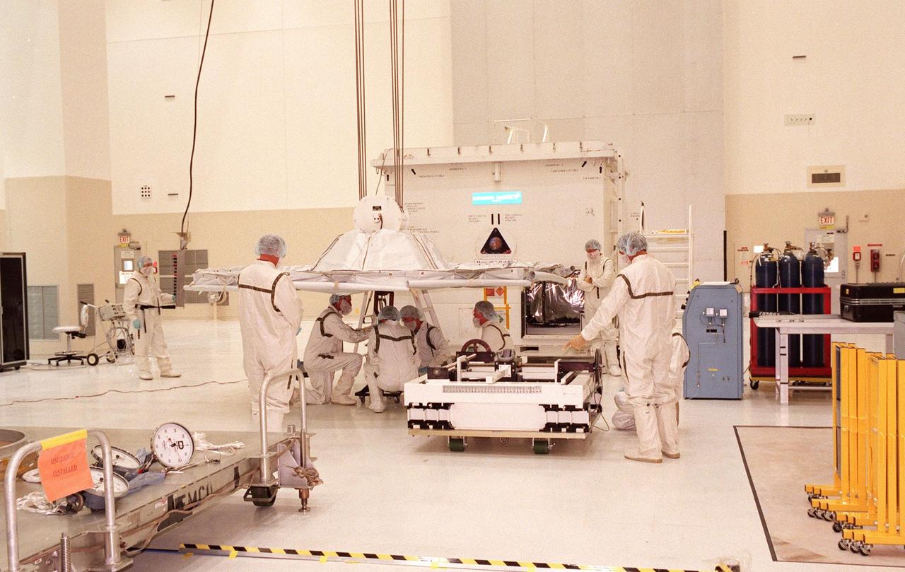 Technicians in the Spacecraft Assembly and Encapsulation Facility-2 (SAEF-2) prepare a lifting device they will use to remove the Mars Climate Orbiter from its container (behind the workers). The Mars Climate Orbiter is heading for Mars where it will primarily support its companion Mars Polar Lander spacecraft, planned for launch on Jan. 3, 1999. After that, the Mars Climate Orbiter's instruments will monitor the Martian atmosphere and image the planet's surface on a daily basis for one Martian year (two Earth years). It will observe the appearance and movement of atmospheric dust and water vapor, as well as characterize seasonal changes on the surface. The detailed images of the surface features will provide important clues to the planet's early climate history and give scientists more information about possible liquid water reserves beneath the surface. The scheduled launch date for the Mars Climate Orbiter is Dec. 10, 1998, on a Boeing Delta II 7425 rocket