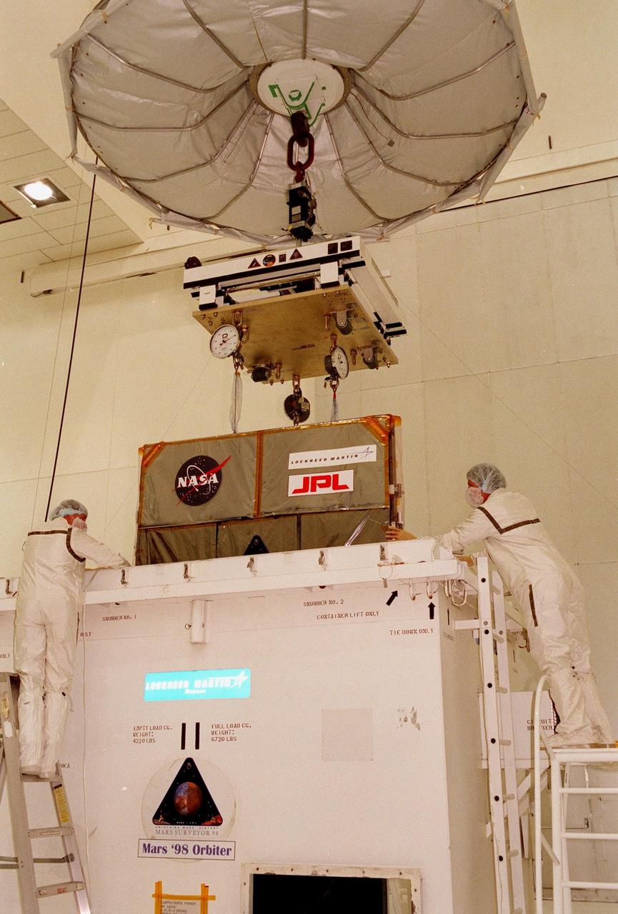 Technicians in the Spacecraft Assembly and Encapsulation Facility-2 (SAEF-2) oversee the removal of the Mars Climate Orbiter from its container. The Mars Climate Orbiter is heading for Mars where it will primarily support its companion Mars Polar Lander spacecraft, planned for launch on Jan. 3, 1999. After that, the Mars Climate Orbiter's instruments will monitor the Martian atmosphere and image the planet's surface on a daily basis for one Martian year (two Earth years). It will observe the appearance and movement of atmospheric dust and water vapor, as well as characterize seasonal changes on the surface. The detailed images of the surface features will provide important clues to the planet's early climate history and give scientists more information about possible liquid water reserves beneath the surface. The scheduled launch date for the Mars Climate Orbiter is Dec. 10, 1998, on a Boeing Delta II 7425 rocket