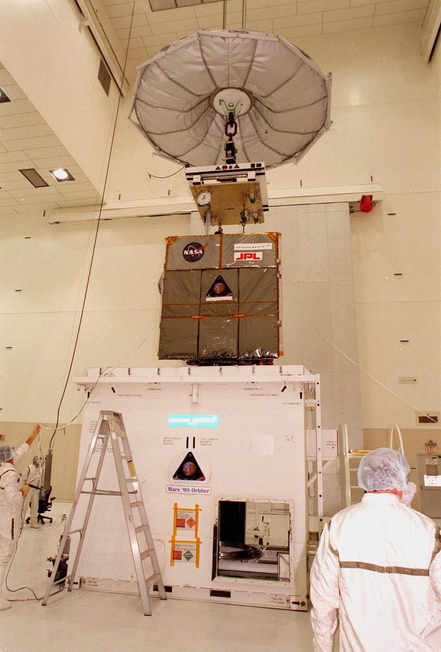 The Mars Climate Orbiter is lifted clear of the top of its container in the Spacecraft Assembly and Encapsulation Facility-2 (SAEF-2). The Mars Climate Orbiter is heading for Mars where it will primarily support its companion Mars Polar Lander spacecraft, planned for launch on Jan. 3, 1999. After that, the Mars Climate Orbiter's instruments will monitor the Martian atmosphere and image the planet's surface on a daily basis for one Martian year (two Earth years). It will observe the appearance and movement of atmospheric dust and water vapor, as well as characterize seasonal changes on the surface. The detailed images of the surface features will provide important clues to the planet's early climate history and give scientists more information about possible liquid water reserves beneath the surface. The scheduled launch date for the Mars Climate Orbiter is Dec. 10, 1998, on a Boeing Delta II 7425 rocket