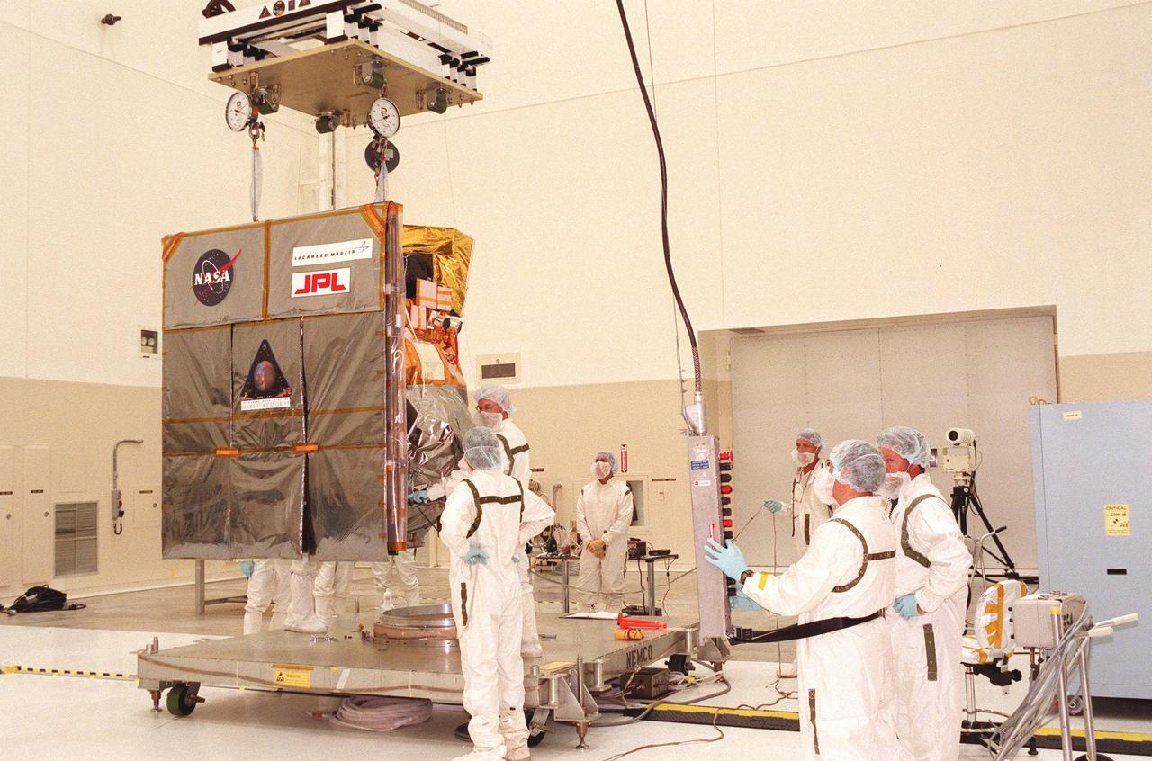 Technicians carefully maneuver the Mars Climate Orbiter toward its workstand in the Spacecraft Assembly and Encapsulation Facility-2 (SAEF-2). The Mars Climate Orbiter is heading for Mars where it will primarily support its companion Mars Polar Lander spacecraft, planned for launch on Jan. 3, 1999. After that, the Mars Climate Orbiter's instruments will monitor the Martian atmosphere and image the planet's surface on a daily basis for one Martian year (two Earth years). It will observe the appearance and movement of atmospheric dust and water vapor, as well as characterize seasonal changes on the surface. The detailed images of the surface features will provide important clues to the planet's early climate history and give scientists more information about possible liquid water reserves beneath the surface. The scheduled launch date for the Mars Climate Orbiter is Dec. 10, 1998, on a Boeing Delta II 7425 rocket