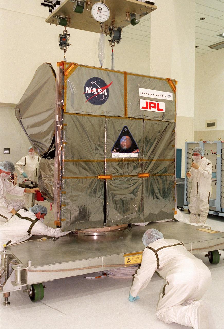 Technicians check the connections on the workstand holding the Mars Climate Orbiter in the Spacecraft Assembly and Encapsulation Facility-2 (SAEF-2). The Mars Climate Orbiter is heading for Mars where it will primarily support its companion Mars Polar Lander spacecraft, planned for launch on Jan. 3, 1999. After that, the Mars Climate Orbiter's instruments will monitor the Martian atmosphere and image the planet's surface on a daily basis for one Martian year (two Earth years). It will observe the appearance and movement of atmospheric dust and water vapor, as well as characterize seasonal changes on the surface. The detailed images of the surface features will provide important clues to the planet's early climate history and give scientists more information about possible liquid water reserves beneath the surface. The scheduled launch date for the Mars Climate Orbiter is Dec. 10, 1998, on a Boeing Delta II 7425 rocket