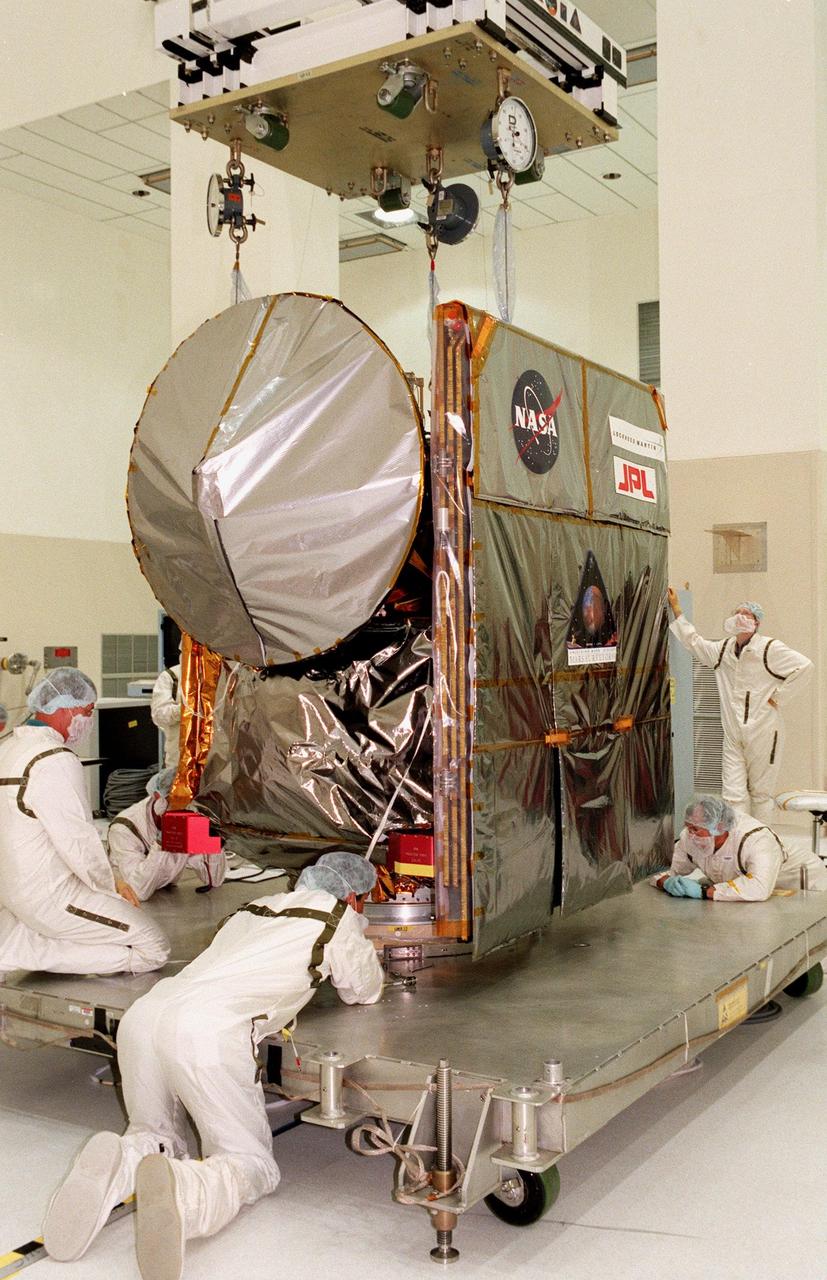 Technicians check the connections on the workstand holding the Mars Climate Orbiter in the Spacecraft Assembly and Encapsulation Facility-2 (SAEF-2). The Mars Climate Orbiter is heading for Mars where it will primarily support its companion Mars Polar Lander spacecraft, planned for launch on Jan. 3, 1999. After that, the Mars Climate Orbiter's instruments will monitor the Martian atmosphere and image the planet's surface on a daily basis for one Martian year (two Earth years). It will observe the appearance and movement of atmospheric dust and water vapor, as well as characterize seasonal changes on the surface. The detailed images of the surface features will provide important clues to the planet's early climate history and give scientists more information about possible liquid water reserves beneath the surface. The scheduled launch date for the Mars Climate Orbiter is Dec. 10, 1998, on a Boeing Delta II 7425 rocket