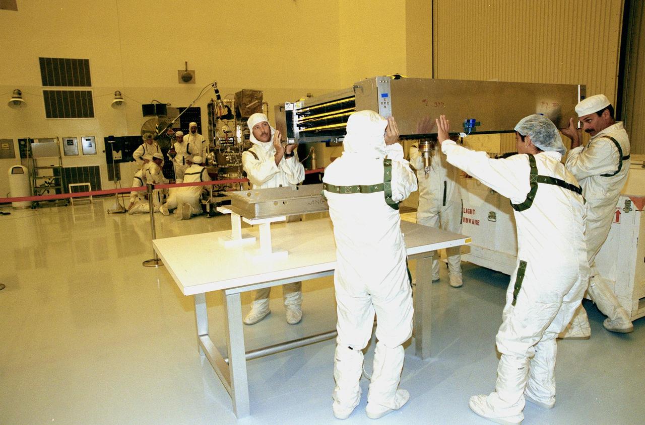 KENNEDY SPACE CENTER, FLA. -- Workers in the Payload Hazardous Servicing Facility remove a solar panel from Deep Space 1 as part of the preparations for launch aboard a Boeing Delta 7326 rocket in October. The first flight in NASA's New Millennium Program, Deep Space 1 is designed to validate 12 new technologies for scientific space missions of the next century. Onboard experiments include an ion propulsion engine and software that tracks celestial bodies so the spacecraft can make its own navigation decisions without the intervention of ground controllers. Most of its mission objectives will be completed within the first two months. A near-Earth asteroid, 1992 KD, has also been selected for a possible flyby