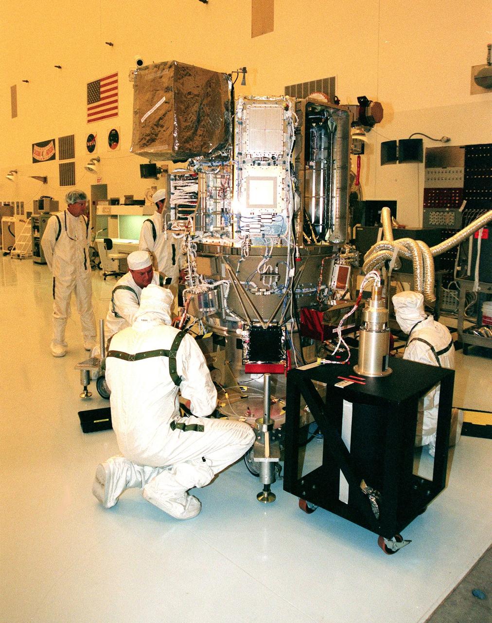 KENNEDY SPACE CENTER, FLA. -- Workers in the Payload Hazardous Servicing Facility check out Deep Space 1 to prepare it for launch aboard a Boeing Delta 7326 rocket in October. The first flight in NASA's New Millennium Program, Deep Space 1 is designed to validate 12 new technologies for scientific space missions of the next century. Onboard experiments include an ion propulsion engine and software that tracks celestial bodies so the spacecraft can make its own navigation decisions without the intervention of ground controllers. Most of its mission objectives will be completed within the first two months. A near-Earth asteroid, 1992 KD, has also been selected for a possible flyby