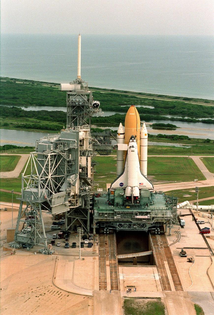 At the end of its 6-hour, 4.2-mile circular trek from the Vehicle Assembly Building, the STS-95 Space Shuttle Discovery sits on the Mobile Launch Platform, still atop the crawler transporter, at Launch Pad 39B. To its left is the Fixed Service Structure that provides access to the orbiter and the Rotating Service Structure. Above it is the 80-foot fiberglass lightning mast which provides protection from lightning strikes. This view shows the Atlantic Ocean beyond the shuttle, to the east. At the launch pad, the orbiter, external tank and solid rocket boosters will undergo final preparations for the launch, scheduled to lift off Oct. 29. The mission includes research payloads such as the Spartan solar-observing deployable spacecraft, the Hubble Space Telescope Orbital Systems Test Platform, the International Extreme Ultraviolet Hitchhiker, as well as the SPACEHAB single module with experiments on space flight and the aging process