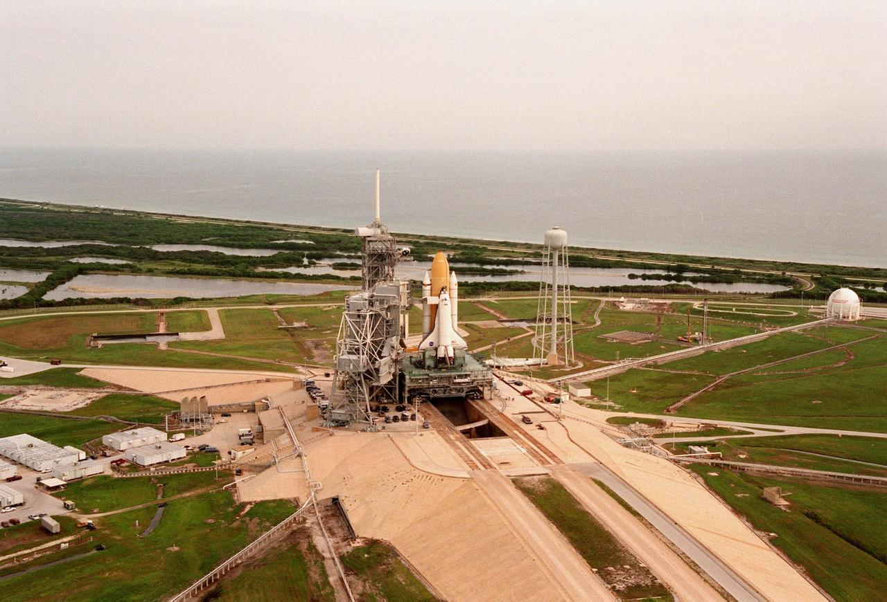 The STS-95 Space Shuttle Discovery sits on the Mobile Launch Platform, still atop the crawler transporter, at Launch Pad 39B. To its left is the Fixed Service Structure that provides access to the orbiter and the Rotating Service Structure. To its right is the elevated water tank, with a capacity of 300,000 gallons. Part of the sound suppression water system, the tank stands 290 feet high on the northeast side of the pad. Water from the tank is released just before ignition of the orbiter's three main engines and twin solid rocket boosters. The entire system reduces the acoustical levels within the orbiter's payload bay to an acceptable 142 decibels. Beyond the orbiter is seen the Atlantic Ocean. While at the launch pad, the orbiter, external tank and solid rocket boosters will undergo final preparations for the launch, scheduled to lift off Oct. 29. The mission includes research payloads such as the Spartan solar-observing deployable spacecraft, the Hubble Space Telescope Orbital Systems Test Platform, the International Extreme Ultraviolet Hitchhiker, as well as the SPACEHAB single module with experiments on space flight and the aging process