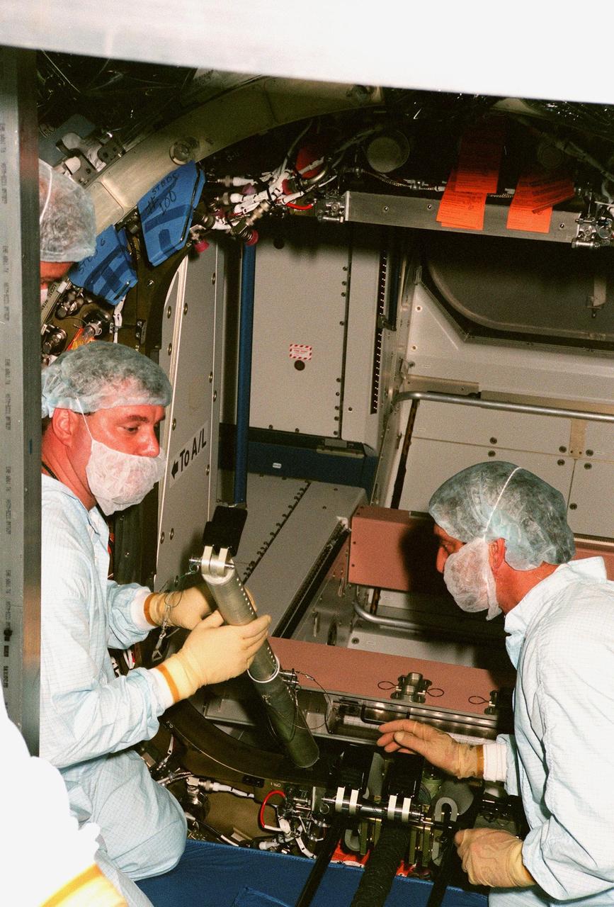 KENNEDY SPACE CENTER, FLA. -- Workers in the Space Station Processing Facility hold part of the equipment to close the hatch to the Unity connecting module, part of the International Space Station, before its launch aboard Space Shuttle Endeavour on STS-88 in December. Unity will now undergo a series of leak checks before a final purge of clean, dry air inside the module to ready it for initial operations in space. Other testing includes the common berthing mechanism to which other space station elements will dock and the Pad Demonstration Test to verify the compatibility of the module with the Space Shuttle as well as the ability of the astronauts to send and receive commands to Unity from the flight deck of the orbiter. The next time the hatch will be opened it will be by astronauts on orbit. Unity is expected to be ready for installation into the payload canister on Oct. 25, and transported to Launch Pad 39-A on Oct. 27. The Unity will be mated to the Russian-built Zarya control module which should already be in orbit at that time