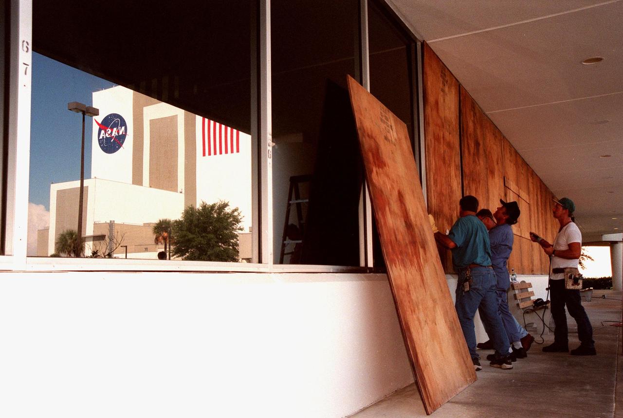 Workers put up plywood barriers on the windows of the Operations Support Building (OSB) as part of a precautionary plan in the event that Hurricane Georges threatens Central Florida. In light of the unpredictable nature of hurricanes, the decision was made to minimize risk and provide protection to KSC personnel and to the Space Shuttle national asset. The Vehicle Assembly Building is reflected (left) in the uncovered windows of the OSB