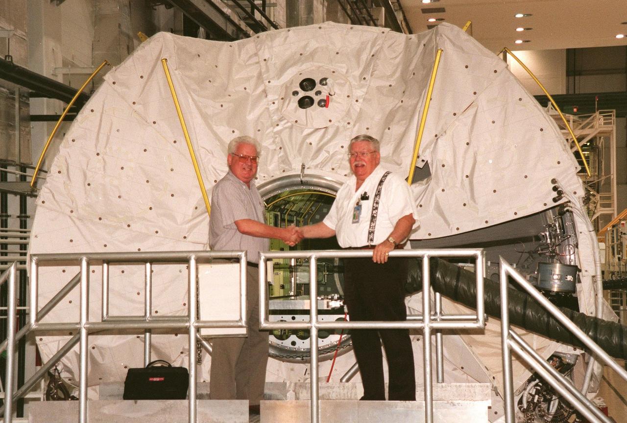 KENNEDY SPACE CENTER, FLA. -- In the Operations and Checkout Building, Rainer Goercke shakes hands with Norman Jatz in front of the Spacelab Module MD001 as they prepare to close it for the last time before shipment to the National Air and Space Museum in Washington, DC. Goercke and Jatz have been on the Spacelab program since 1979 and were part of the team that first unloaded the module at KSC. Goercke is the only remaining European representative from the German-based Spacelab contractor, ERNO, and Jatz is a mechanical engineering lead from Boeing. Spacelab was designed by the European Space Agency (ESA) for the Space Shuttle program. It first flew on STS-9 in November 1983 and its final flight was the STS-90 Neurolab mission in April 1998. The sister module will travel home and be placed on display in Europe. The Spacelab concept of modular experiment racks in a pressurized shirt-sleeve environment made it highly user-friendly and accessible. Numerous experiments conceived by hundreds of scientists on the ground were conducted by flight crews in orbit. Spacelab modules served as on-orbit homes for everything from squirrel monkeys to plant seeds. They supported astronomical as well as Earth observations, for servicing the Hubble Space Telescope and for research preparatory to the International Space Station. One of the greatest benefits afforded by the Spacelab missions was the opportunity to fly a mission more than once, with the second or third flight building on the experiences and data gathered from its predecessors