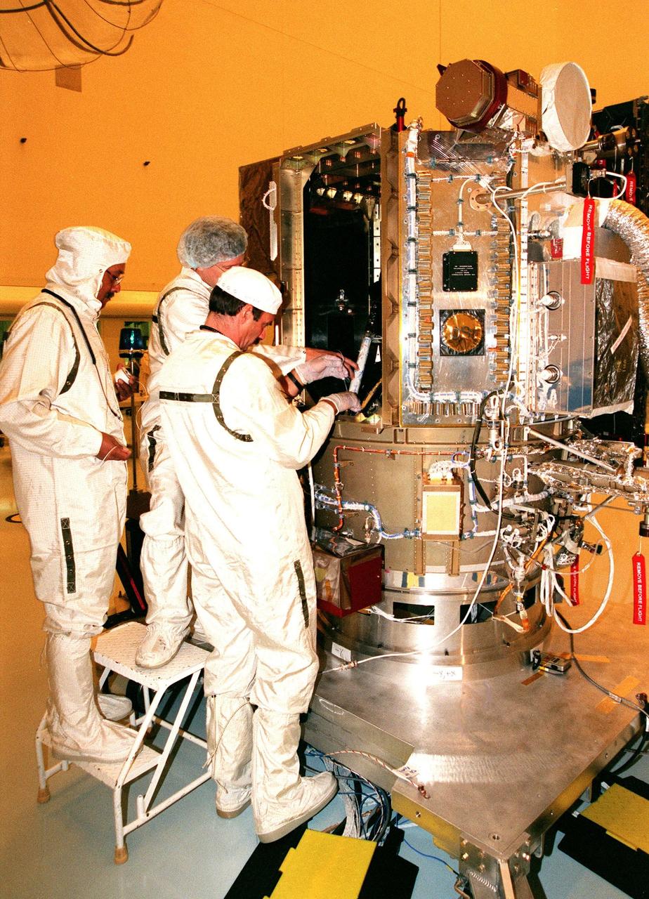 KENNEDY SPACE CENTER, FLA. -- Workers in the Payload Hazardous Servicing Facility (PHSF) place a rolled-up document inside Deep Space 1. The paper was signed by the workers in the PHSF. Deep Space 1 is scheduled to fly on the Boeing Delta 7326 rocket to be launched in October. The first flight in NASA's New Millennium Program, Deep Space 1 is designed to validate 12 new technologies for scientific space missions of the next century. Onboard experiments include an ion propulsion engine and software that tracks celestial bodies so the spacecraft can make its own navigation decisions without the intervention of ground controllers. Deep Space 1 will complete most of its mission objectives within the first two months, but will also do a flyby of a near-Earth asteroid, 1992 KD, in July 1999