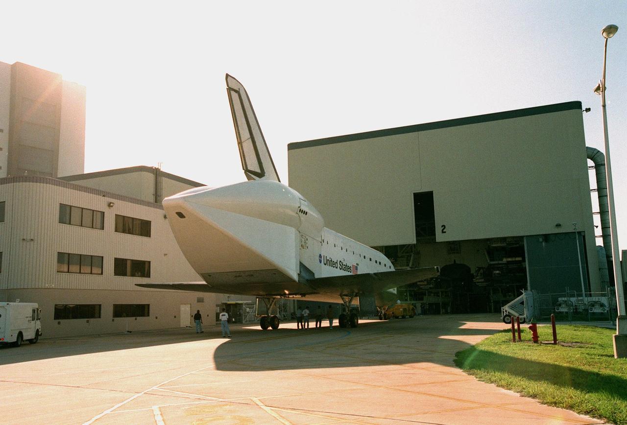 Seen from behind, the orbiter Atlantis approaches the entrance of Orbiter Processing Facility 2 (OPF-2) where it will undergo preparations for its planned flight in June 1999. Atlantis spent 10 months in Palmdale, CA, undergoing extensive inspections and modifications in the orbiter processing facility there. The modifications included several upgrades enabling it to support International Space Station missions, such as adding an external airlock for ISS docking missions and installing thinner, lighter thermal protection blankets for weight reduction which will allow it to haul heavier cargo. OPF-2 consists of a 2,700-square-meter (29,000 square ft.) high bay. The building measures 29 meters (95 ft). high, 121 meters (397 ft.) long and 71 meters (233 ft.) wide