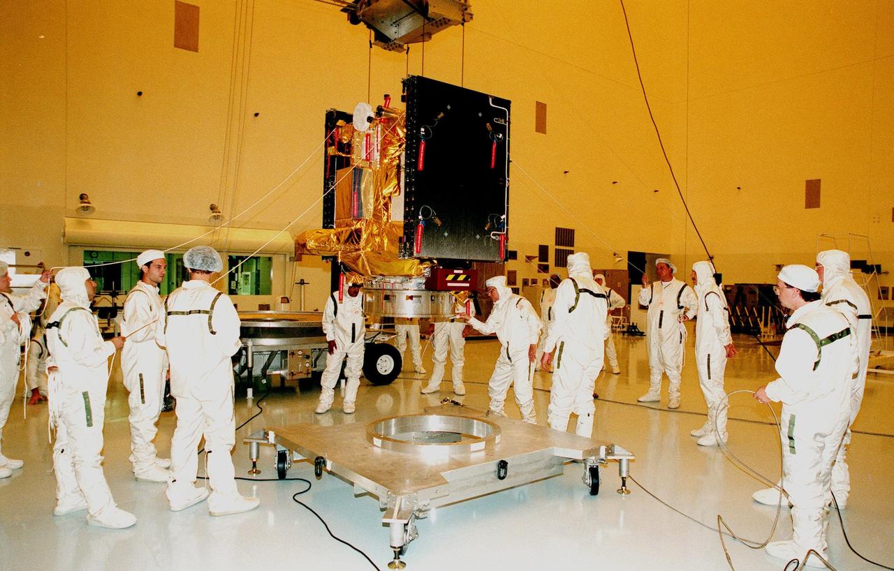 KENNEDY SPACE CENTER, FLA. -- After covering the bulk of Deep Space 1 in thermal insulating blankets, workers in the Payload Hazardous Servicing Facility lift it from its work platform before moving it onto its transporter (behind workers at left). Deep Space 1 is being moved to the Defense Satellite Communications System Processing Facility (DPF), Cape Canaveral Air Station, for testing. At either side of the spacecraft are its solar wings, folded for launch. When fully extended, the wings measure 38.6 feet from tip to tip. The first flight in NASA's New Millennium Program, Deep Space 1 is designed to validate 12 new technologies for scientific space missions of the next century. Onboard experiments include a solar-powered ion propulsion engine and software that tracks celestial bodies so the spacecraft can make its own navigation decisions without the intervention of ground controllers. The ion propulsion engine is the first non-chemical propulsion to be used as the primary means of propelling a spacecraft. Deep Space 1 will complete most of its mission objectives within the first two months, but may also do a flyby of a near-Earth asteroid, 1992 KD, in July 1999. Deep Space 1 will be launched aboard a Boeing Delta 7326 rocket from Launch Pad 17A, Cape Canaveral Air Station, in October. Delta II rockets are medium capacity expendable launch vehicles derived from the Delta family of rockets built and launched since 1960. Since then there have been more than 245 Delta launches