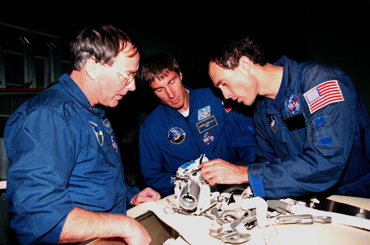 KENNEDY SPACE CENTER, FLA. -- In the Orbiter Processing Facility Bay 1, STS-88 Mission Specialists (left to right) Jerry L. Ross; Sergei Krikalev, a cosmonaut from Russia; and James H. Newman examine equipment that will be on the Space Shuttle Endeavour during their upcoming flight. Launch of Mission STS-88 is targeted for Dec. 3, 1998. The STS-88 crew members are participating in a Crew Equipment Interface Test (CEIT), familiarizing themselves with the orbiter's midbody and crew compartments. Other crew members are Commander Robert D. Cabana, Pilot Frederick W. "Rick" Sturckow and Mission Specialist Nancy J. Currie. STS-88 will be the first Space Shuttle launch for assembly of the International Space Station (ISS). The primary payload is the Unity connecting module which will be mated to the Russian-built Zarya control module, expected to be already on orbit after a November launch from Russia. The first major U.S.-built component of ISS, Unity will serve as a connecting passageway to living and working areas of the space station. Unity has two attached pressurized mating adapters (PMAs) and one stowage rack installed inside. PMA-1 provides the permanent connection point between Unity and Zarya; PMA-2 will serve as a Space Shuttle docking port. Zarya is a self-supporting active vehicle, providing propulsive control capability and power during the early assembly stages. It also has fuel storage capability