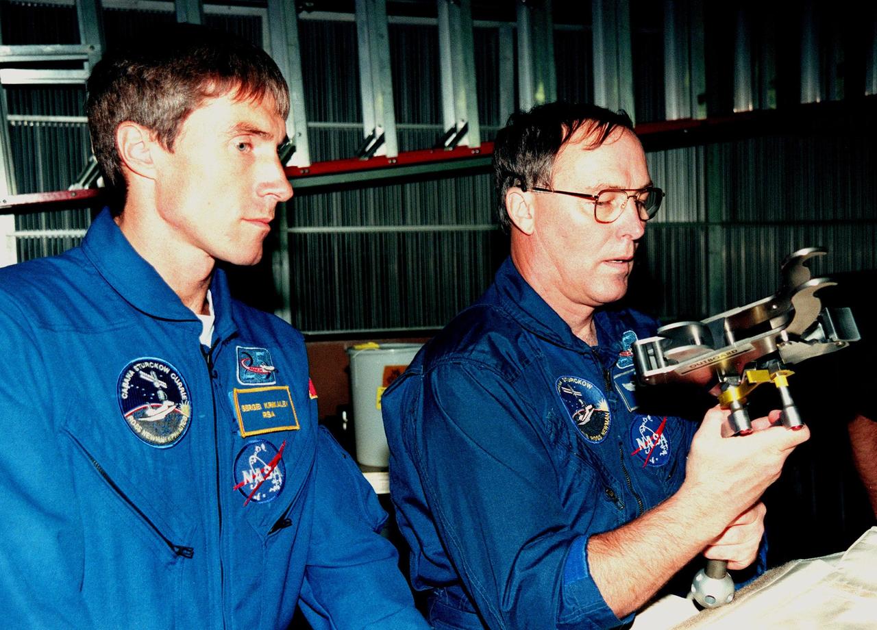 KENNEDY SPACE CENTER, FLA. -- In the Orbiter Processing Facility Bay 1, STS-88 Mission Specialists Sergei Krikalev (left), a cosmonaut from Russia; and Jerry L. Ross examine equipment that will be aboard Space Shuttle Endeavour. Launch of mission STS-88 is targeted for Dec. 3, 1998. The STS-88 crew members are participating in a Crew Equipment Interface Test (CEIT), familiarizing themselves with the orbiter's midbody and crew compartments. Other crew members are Commander Robert D. Cabana, Pilot Frederick W. "Rick" Sturckow and Mission Specialists Nancy J. Currie and James H. Newman. STS-88 will be the first Space Shuttle launch for assembly of the International Space Station (ISS). The primary payload is the Unity connecting module which will be mated to the Russian-built Zarya control module, expected to be already on orbit after a November launch from Russia. The first major U.S.-built component of ISS, Unity will serve as a connecting passageway to living and working areas of the space station. Unity has two attached pressurized mating adapters (PMAs) and one stowage rack installed inside. PMA-1 provides the permanent connection point between Unity and Zarya; PMA-2 will serve as a Space Shuttle docking port. Zarya is a self-supporting active vehicle, providing propulsive control capability and power during the early assembly stages. It also has fuel storage capability