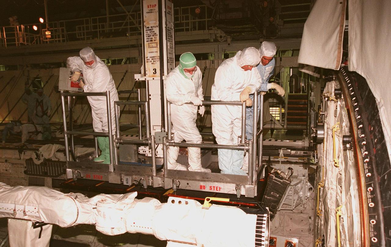 KENNEDY SPACE CENTER, FLA. -- Inside the payload bay of Space Shuttle orbiter Endeavour, workers and STS-88 crew members on a movable work platform or bucket move closer to the rear of the orbiter's crew compartment. While Endeavour is being prepared for flight inside Orbiter Processing Facility Bay 1, the STS-88 crew members are participating in a Crew Equipment Interface Test (CEIT) to familiarize themselves with the orbiter's midbody and crew compartments. A KSC worker (left) maneuvers the platform to give Mission Specialists Jerry L. Ross and James H. Newman (right) a closer look. Looking on is Wayne Wedlake of United Space Alliance at Johnson Space Center. Targeted for liftoff on Dec. 3, 1998, STS-88 will be the first Space Shuttle launch for assembly of the International Space Station (ISS). The primary payload is the Unity connecting module which will be mated to the Russian-built Zarya control module, expected to be already on orbit after a November launch from Russia. After the mating, Ross and Newman are scheduled to perform three spacewalks to connect power, data and utility lines and install exterior equipment. The first major U.S.-built component of ISS, Unity will serve as a connecting passageway to living and working areas of the space station. Unity has two attached pressurized mating adapters (PMAs) and one stowage rack installed inside. PMA-1 provides the permanent connection point between Unity and Zarya; PMA-2 will serve as a Space Shuttle docking port. Zarya is a self-supporting active vehicle, providing propulsive control capability and power during the early assembly stages. It also has fuel storage capability