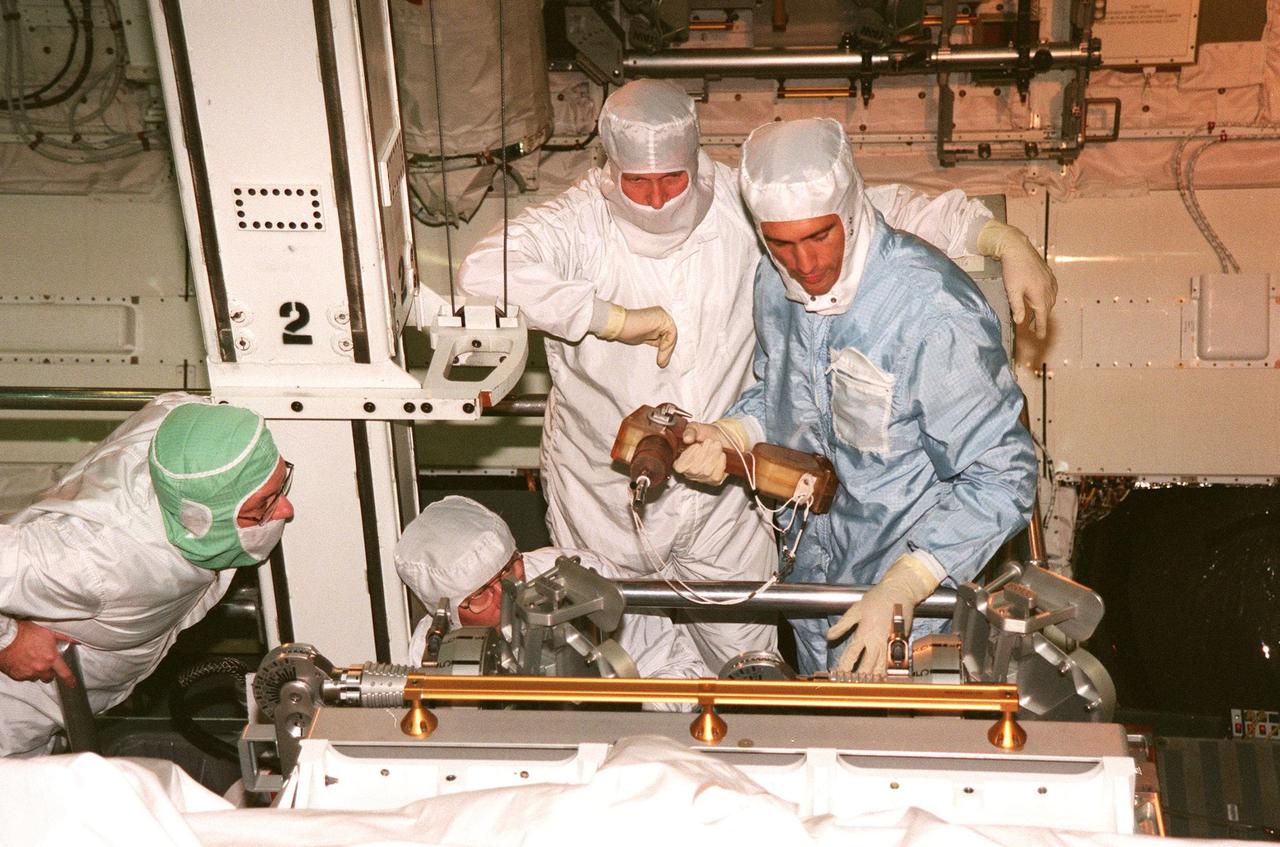 KENNEDY SPACE CENTER, FLA. -- Inside the payload bay of Space Shuttle orbiter Endeavour in Orbiter Processing Facility Bay 1, STS-88 Mission Specialists Jerry L. Ross (crouching at left) and James H. Newman (far right) get a close look at equipment. Looking on is Wayne Wedlake (far left), with United Space Alliance at Johnson Space Center, and a KSC worker (behind Newman) who is operating the movable work platform or bucket. The STS-88 crew members are participating in a Crew Equipment Interface Test (CEIT), familiarizing themselves with the orbiter's midbody and crew compartments. Targeted for liftoff on Dec. 3, 1998, STS-88 will be the first Space Shuttle launch for assembly of the International Space Station (ISS). The primary payload is the Unity connecting module which will be mated to the Russian-built Zarya control module, expected to be already on orbit after a November launch from Russia. After the mating, Ross and Newman are scheduled to perform three spacewalks to connect power, data and utility lines and install exterior equipment. The first major U.S.-built component of ISS, Unity will serve as a connecting passageway to living and working areas of the space station. Unity has two attached pressurized mating adapters (PMAs) and one stowage rack installed inside. PMA-1 provides the permanent connection point between Unity and Zarya; PMA-2 will serve as a Space Shuttle docking port. Zarya is a self-supporting active vehicle, providing propulsive control capability and power during the early assembly stages. It also has fuel storage capability