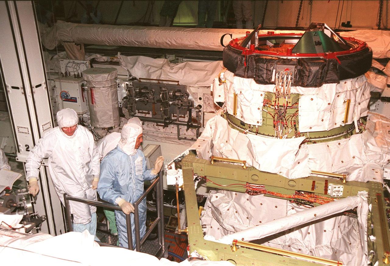 KENNEDY SPACE CENTER, FLA. -- Inside the payload bay of orbiter Endeavour in the Orbiter Processing Facility Bay 1, STS-88 Mission Specialists Jerry L. Ross (left) and James H. Newman (right foreground) get a close look at the Orbiter Docking System. The STS-88 crew members are participating in a Crew Equipment Interface Test (CEIT), familiarizing themselves with the orbiter's midbody and crew compartments. Targeted for liftoff on Dec. 3, 1998, STS-88 will be the first Space Shuttle launch for assembly of the International Space Station (ISS). The primary payload is the Unity connecting module which will be mated to the Russian-built Zarya control module, expected to be already on orbit after a November launch from Russia. While on orbit during STS-88, Unity will be latched atop the Orbiter Docking System in the forward section of Endeavour's payload bay for the mating of the two modules. After the mating, Ross and Newman are scheduled to perform three spacewalks to connect power, data and utility lines and install exterior equipment. The first major U.S.-built component of ISS, Unity will serve as a connecting passageway to living and working areas of the space station. Unity has two attached pressurized mating adapters (PMAs) and one stowage rack installed inside. PMA-1 provides the permanent connection point between Unity and Zarya; PMA-2 will serve as a Space Shuttle docking port. Zarya is a self-supporting active vehicle, providing propulsive control capability and power during the early assembly stages. It also has fuel storage capability