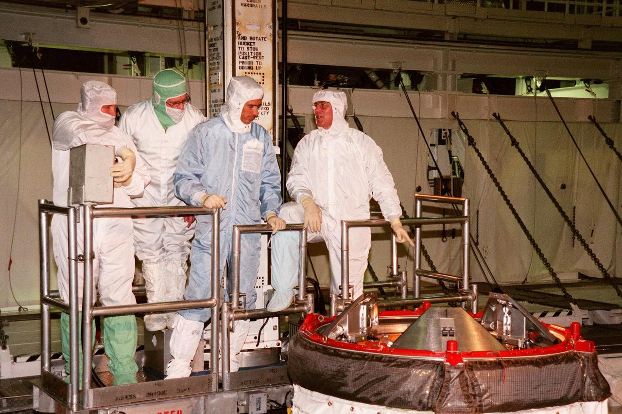KENNEDY SPACE CENTER, FLA. -- Lowered on a movable work platform or bucket inside the payload bay of orbiter Endeavour, STS-88 Mission Specialists Jerry L. Ross (far right) and James H. Newman (second from right) get a close look at the Orbiter Docking System. At left is the bucket operator and Wayne Wedlake, with United Space Alliance at Johnson Space Center. The STS-88 crew members are in Orbiter Processing Facility Bay 1 to participate in a Crew Equipment Interface Test (CEIT) to familiarize themselves with the orbiter's midbody and crew compartments. Targeted for liftoff on Dec. 3, 1998, STS-88 will be the first Space Shuttle launch for assembly of the International Space Station (ISS). The primary payload is the Unity connecting module which will be mated to the Russian-built Zarya control module, expected to be already on orbit after a November launch from Russia. While on orbit during STS-88, Unity will be latched atop the Orbiter Docking System in the forward section of Endeavour's payload bay for the mating of the two modules. After the mating, Ross and Newman are scheduled to perform three spacewalks to connect power, data and utility lines and install exterior equipment. The first major U.S.-built component of ISS, Unity will serve as a connecting passageway to living and working areas of the space station. Unity has two attached pressurized mating adapters (PMAs) and one stowage rack installed inside. PMA-1 provides the permanent connection point between Unity and Zarya; PMA-2 will serve as a Space Shuttle docking port. Zarya is a self-supporting active vehicle, providing propulsive control capability and power during the early assembly stages. It also has fuel storage capability