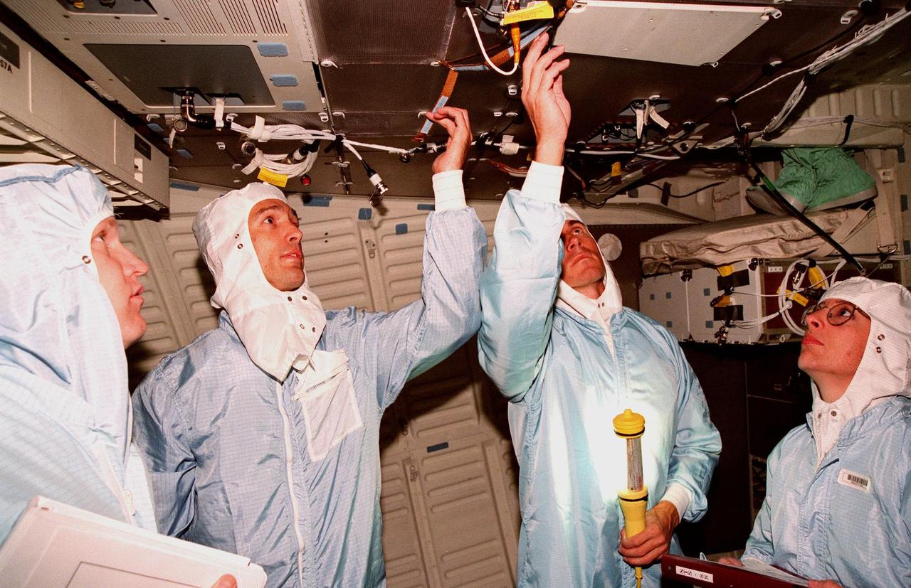 KENNEDY SPACE CENTER, FLA. -- Inside Space Shuttle orbiter Endeavour in the Orbiter Processing Facility Bay 1, workers James Neilhouse (left) and Melissa Groening (right) watch while STS-88 Mission Specialists James H. Newman (second from left) and Sergei Krikalev, a Russian cosmonaut, check overhead equipment. STS-88 crew members are participating in a Crew Equipment Interface Test (CEIT), familiarizing themselves with the orbiter's midbody and crew compartments. Targeted for liftoff on Dec. 3, 1998, STS-88 will be the first Space Shuttle launch for assembly of the International Space Station (ISS). The primary payload is the Unity connecting module which will be mated to the Russian-built Zarya control module, expected to be already on orbit after a November launch from Russia. The first major U.S.-built component of ISS, Unity will serve as a connecting passageway to living and working areas of the space station. Unity has two attached pressurized mating adapters (PMAs) and one stowage rack installed inside. PMA-1 provides the permanent connection point between Unity and Zarya; PMA-2 will serve as a Space Shuttle docking port. Zarya is a self-supporting active vehicle, providing propulsive control capability and power during the early assembly stages. It also has fuel storage capability.