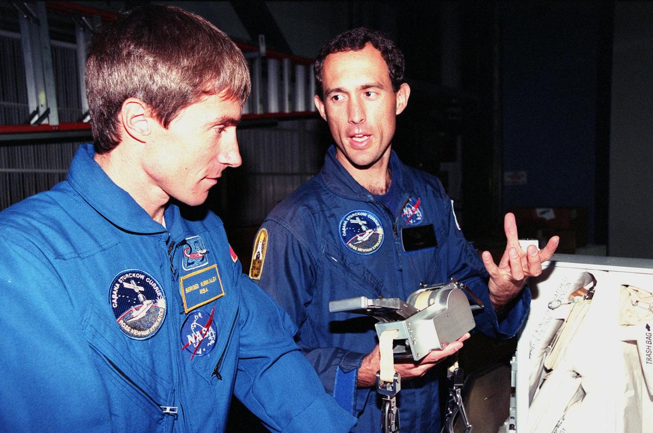 KENNEDY SPACE CENTER, FLA. -- Inside the Orbiter Processing Facility Bay 1, STS-88 Mission Specialists Sergei Krikalev (left), a Russian cosmonaut; and James H. Newman look over equipment for their upcoming flight. The STS-88 crew members are participating in a Crew Equipment Interface Test (CEIT), familiarizing themselves with the orbiter's midbody and crew compartments. Targeted for liftoff on Dec. 3, 1998, STS-88 will be the first Space Shuttle launch for assembly of the International Space Station (ISS). The primary payload is the Unity connecting module which will be mated to the Russian-built Zarya control module, expected to be already on orbit after a November launch from Russia. The first major U.S.-built component of ISS, Unity will serve as a connecting passageway to living and working areas of the space station. Unity has two attached pressurized mating adapters (PMAs) and one stowage rack installed inside. PMA-1 provides the permanent connection point between Unity and Zarya; PMA-2 will serve as a Space Shuttle docking port. Zarya is a self-supporting active vehicle, providing propulsive control capability and power during the early assembly stages. It also has fuel storage capability