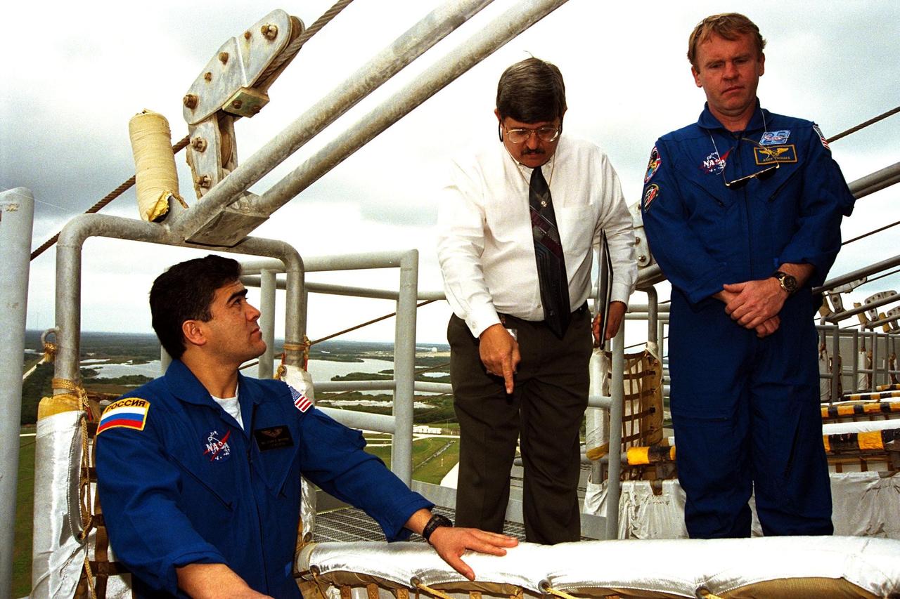 KENNEDY SPACE CENTER, Fla. -- STS-89 Mission Specialist Salizhan Sharipov of the Russian Space Agency stands in a slidewire basket on the emergency egress system at KSC’s Launch Pad 39A, as Jim Bell, USA senior instructor for technical training, explains the egress system to him and to STS-89 Mission Specialist Andrew Thomas, Ph.D, at right. Dr. Thomas will transfer to the Russian Space Station Mir and succeed David Wolf, M.D., who will return to Earth aboard Endeavour. The seven astronauts assigned to the eighth Shuttle-Mir docking flight are completing Terminal Countdown Demonstration Test (TCDT) activities. A dress rehearsal for launch, the TCDT includes emergency egress training at the launch pad and culminates with a simulated countdown. The Space Shuttle Endeavour is undergoing preparations for liftoff, scheduled for Jan. 22. Dr. Thomas will live and work on Mir until June