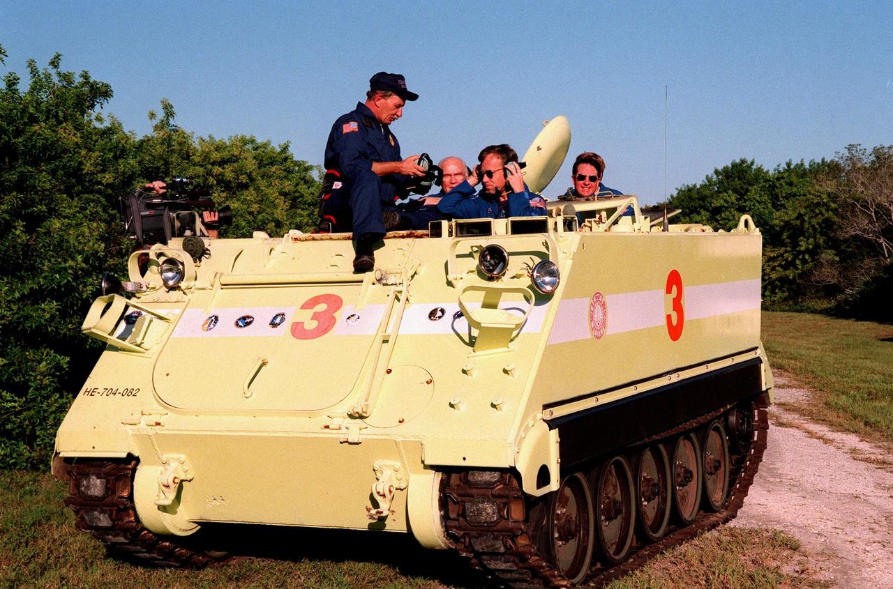 Capt. George Hoggard (left), trainer with the KSC Fire Department, reviews procedures with STS-95 crew members before beginning training on the M-113, a small armored personnel carrier, that is part of emergency egress training. Pilot Steven W. Lindsey (front right) prepares to take his turn in the driver seat, with Payload Specialists John H. Glenn Jr. (rear left) and Stephen K. Robinson (right) as passengers. The tracked vehicle could be used by the crew in the event of an emergency at the pad during which the crew must make a quick exit from the area. The STS-95 crew is at KSC to participate in a Terminal Countdown Demonstration Test (TCDT) which also includes mission familiarization activities and a simulated main engine cut-off exercise. The other members on the mission are Mission Commander Curtis L. Brown, Mission Specialists Scott E. Parazynski and Pedro Duque of Spain, representing the European Space Agency (ESA); and Payload Specialist Chiaki Mukai, representing the National Space Development Agency of Japan (NASDA). STS-95, which is targeted for launch on Oct. 29, 1998, includes research payloads such as the Spartan solar-observing deployable spacecraft, the Hubble Space Telescope Orbital Systems Test Platform, the International Extreme Ultraviolet Hitchhiker, as well as the SPACEHAB single module with experiments on space flight and the aging process