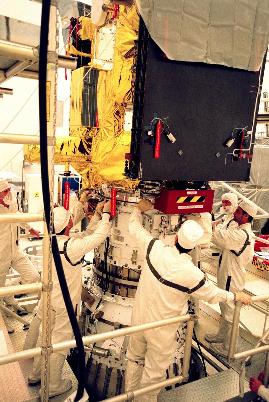 KENNEDY SPACE CENTER, FLA. -- Workers at the Defense Satellite Communications System Processing Facility (DPF), Cape Canaveral Air Station (CCAS), install an ion propulsion engine on Deep Space 1. The first flight in NASA's New Millennium Program, Deep Space 1 is designed to validate 12 new technologies for scientific space missions of the next century, including the engine. Propelled by the gas xenon, the engine is being flight-tested for future deep space and Earth-orbiting missions. Deceptively powerful, the ion drive emits only an eerie blue glow as ionized atoms of xenon are pushed out of the engine. While slow to pick up speed, over the long haul it can deliver 10 times as much thrust per pound of fuel as liquid or solid fuel rockets. Other onboard experiments include software that tracks celestial bodies so the spacecraft can make its own navigation decisions without the intervention of ground controllers. Deep Space 1 will complete most of its mission objectives within the first two months, but will also do a flyby of a near-Earth asteroid, 1992 KD, in July 1999. Deep Space 1 will be launched aboard a Boeing Delta 7326 rocket from Launch Pad 17A, CCAS, in October