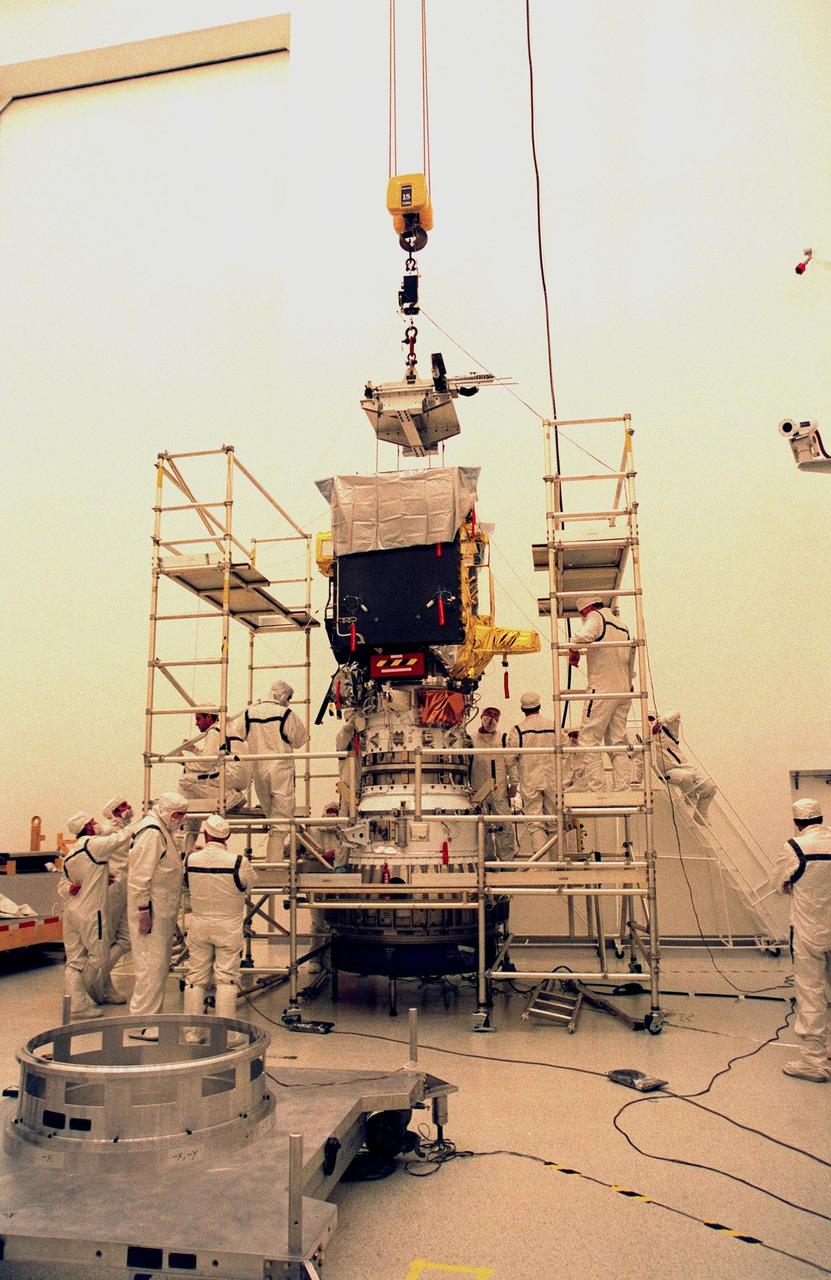 KENNEDY SPACE CENTER, FLA. -- Workers in the Defense Satellite Communications Systems Processing Facility (DPF) at Cape Canaveral Air Station (CCAS) finish installing the ion propulsion engine on Deep Space 1. The first flight in NASA's New Millennium Program, Deep Space 1 is designed to validate 12 new technologies for scientific space missions of the next century, including the engine. Propelled by the gas xenon, the engine is being flight-tested for future deep space and Earth-orbiting missions. Deceptively powerful, the ion drive emits only an eerie blue glow as ionized atoms of xenon are pushed out of the engine. While slow to pick up speed, over the long haul it can deliver 10 times as much thrust per pound of fuel as liquid or solid fuel rockets. Other onboard experiments include software that tracks celestial bodies so the spacecraft can make its own navigation decisions without the intervention of ground controllers. Deep Space 1 will complete most of its mission objectives within the first two months, but will also do a flyby of a near-Earth asteroid, 1992 KD, in July 1999. Deep Space 1 will be launched Oct. 25 aboard a Boeing Delta 7326 rocket from Launch Pad 17A, CCAS