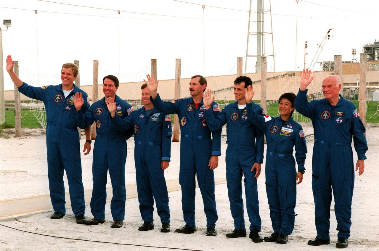 Near the slide wire basket drop point on Launch Pad 39-B, the STS-95 crew wave at 106 reporters and photographers during a brief break from the Terminal Countdown Demonstration Test (TCDT) to answer questions about the mission and training. The crew were at the pad for emergency egress training after the break. Mission Commander Curtis L. Brown (center) introduced the rest of the crew: (left to right) Mission Specialist Scott E. Parazynski, Mission Specialist Stephen K. Robinson, who also serves as Payload Commander, Pilot Steven W. Lindsey, (Brown), Mission Specialist Pedro Duque of Spain, representing the European Space Agency (ESA), Payload Specialist Chiaki Mukai, representing the National Space Development Agency of Japan (NASDA), and Payload Specialist John H. Glenn Jr., senator from Ohio. The TCDT also involves mission familiarization activities and a simulated main engine cut-off exercise. The STS-95 mission, targeted for liftoff on Oct. 29, includes research payloads such as the Spartan solar-observing deployable spacecraft, the Hubble Space Telescope Orbital Systems Test Platform, the International Extreme Ultraviolet Hitchhiker, as well as the SPACEHAB single module with experiments on space flight and the aging process. Following the TCDT, the crew will be returning to Houston for final flight preparations