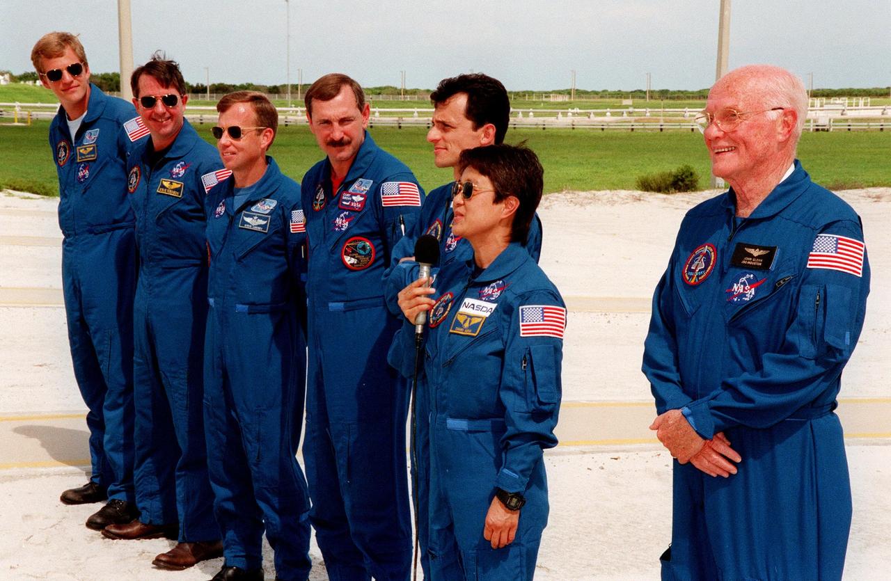 Near Launch Pad 39-B, STS-95 Payload Specialist Chiaki Mukai (second from right), representing the National Space Development Agency of Japan (NASDA), responds to questions about the mission and training from reporters during a brief break from the Terminal Countdown Demonstration Test (TCDT). Other crew members also participated: (from left) Mission Specialist Scott E. Parazynski, Mission Specialist Stephen K. Robinson, who also serves as Payload Commander, Pilot Steven W. Lindsey, Mission Commander Curtis L. Brown, Mission Specialist Pedro Duque of Spain, representing the European Space Agency (ESA), (Mukai), and Payload Specialist John H. Glenn Jr., senator from Ohio. The crew were at the pad for emergency egress training after the break. The TCDT also involves mission familiarization activities and a simulated main engine cut-off exercise. The STS-95 mission, targeted for liftoff on Oct. 29, includes research payloads such as the Spartan solar-observing deployable spacecraft, the Hubble Space Telescope Orbital Systems Test Platform, the International Extreme Ultraviolet Hitchhiker, as well as the SPACEHAB single module with experiments on space flight and the aging process. Following the TCDT, the crew will be returning to Houston for final flight preparations