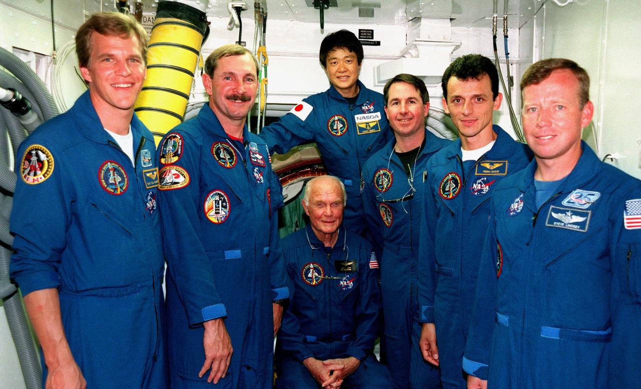At Launch Pad 39-B, the STS-95 crew pose for a closeup photo while in the white room, an environmental chamber that mates with the orbiter and can provide emergency egress for the flight crew before launch. The white room is the outer end of the orbiter access arm, which is part of the fixed service structure on the pad. Pictured are (left to right) Mission Specialist Scott E. Parazynski, Mission Commander Curtis L. Brown, Payload Specialist John H. Glenn Jr. (seated), senator from Ohio, Payload Specialist Chiaki Mukai (behind Glenn), representing the National Space Development Agency of Japan (NASDA), Mission Specialist Stephen K. Robinson, Mission Specialist Pedro Duque of Spain, representing the European Space Agency (ESA), and Pilot Steven W. Lindsey. The STS-95 crew are at KSC to participate in a Terminal Countdown Demonstration Test (TCDT) which includes mission familiarization activities, emergency egress training, and a simulated main engine cut-off exercise. The STS-95 mission, targeted for liftoff on Oct. 29, includes research payloads such as the Spartan solar-observing deployable spacecraft, the Hubble Space Telescope Orbital Systems Test Platform, the International Extreme Ultraviolet Hitchhiker, as well as the SPACEHAB single module with experiments on space flight and the aging process. Following the TCDT, the crew will be returning to Houston for final flight preparations